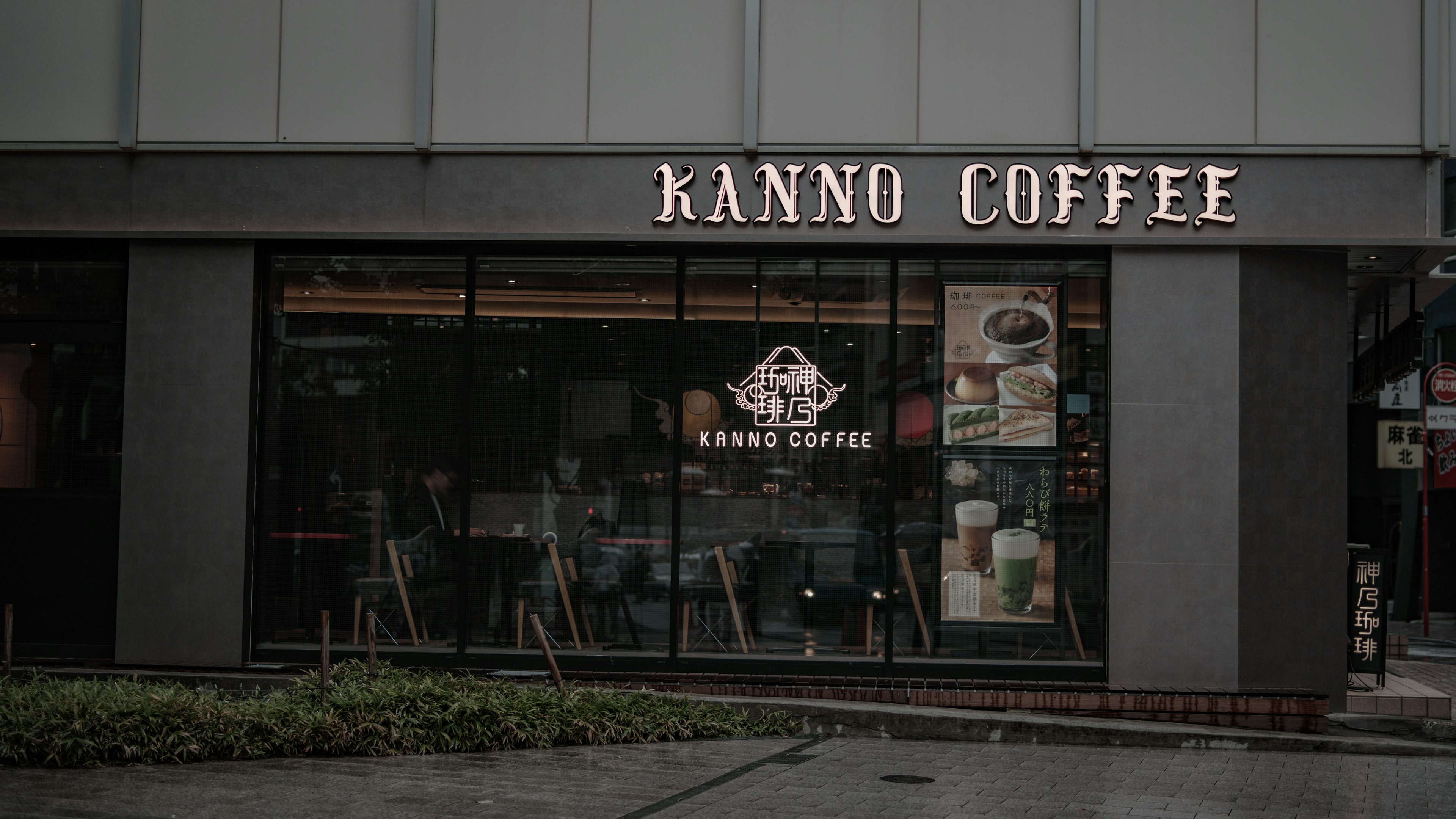 Außenansicht von Kanno Coffee mit heller Beschilderung und Glasfenstern, die das Innere zeigen