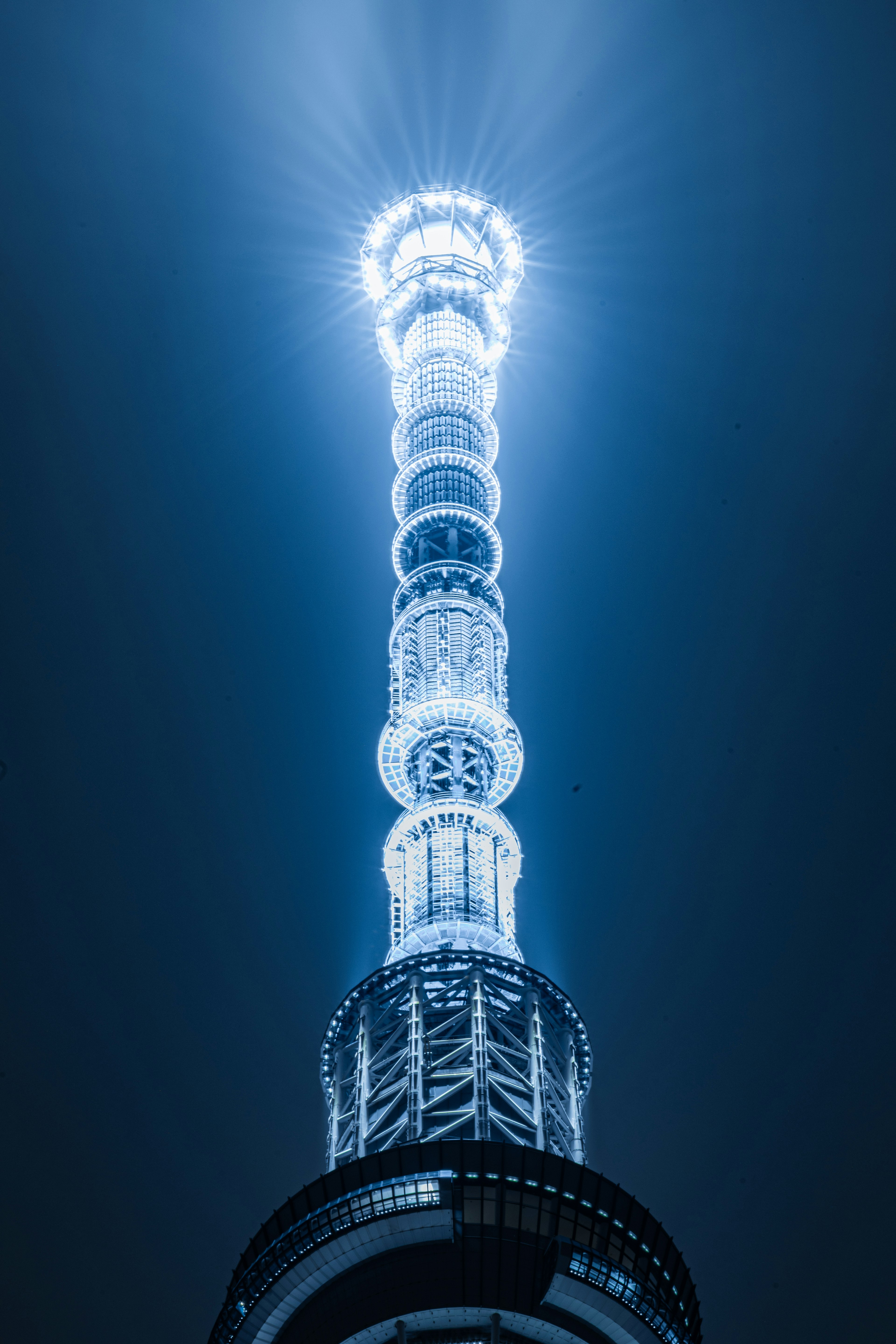 La partie supérieure d'une tour illuminée par une lumière bleuâtre dans le ciel nocturne