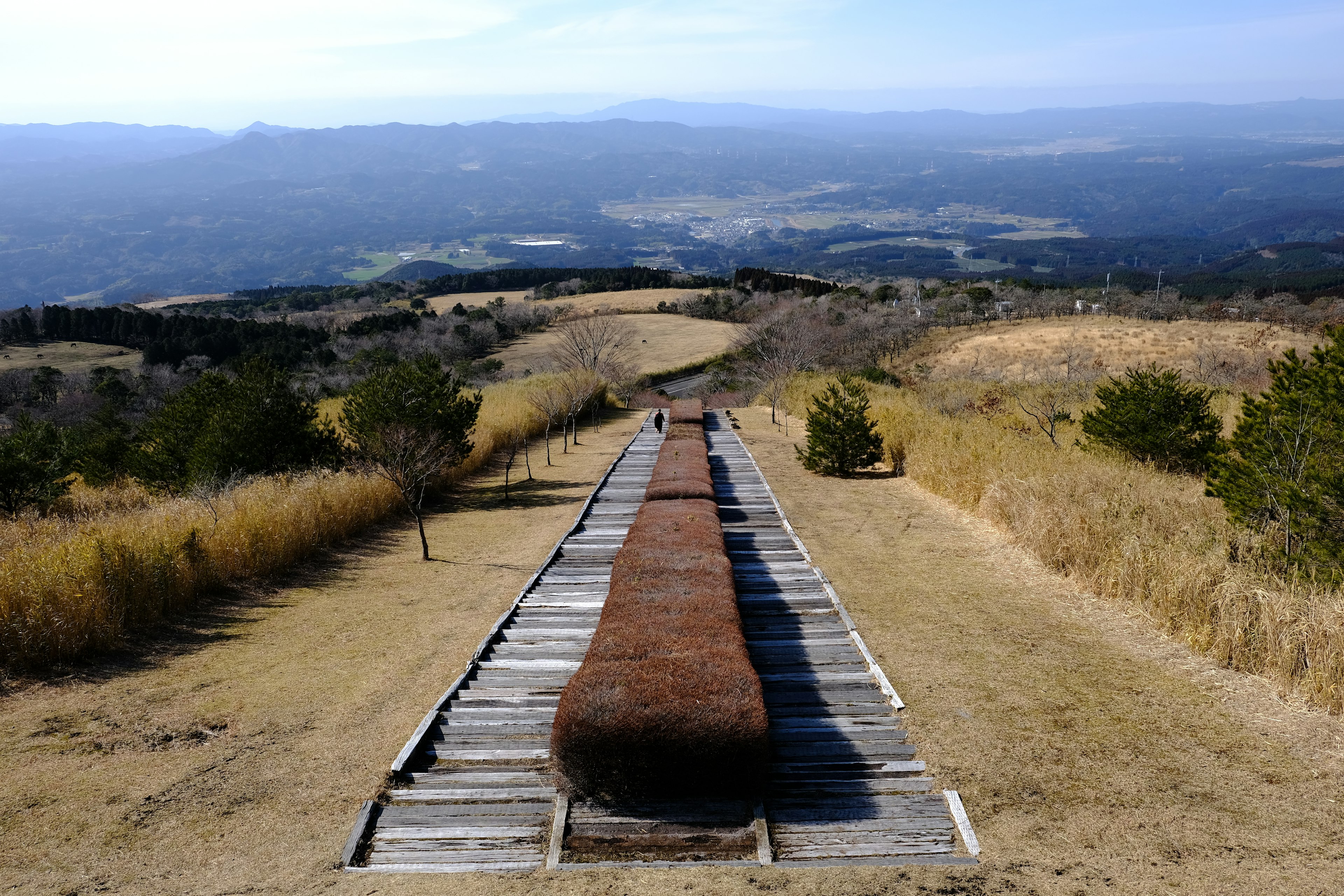 Struktur kayu panjang dengan latar belakang padang rumput dan gunung