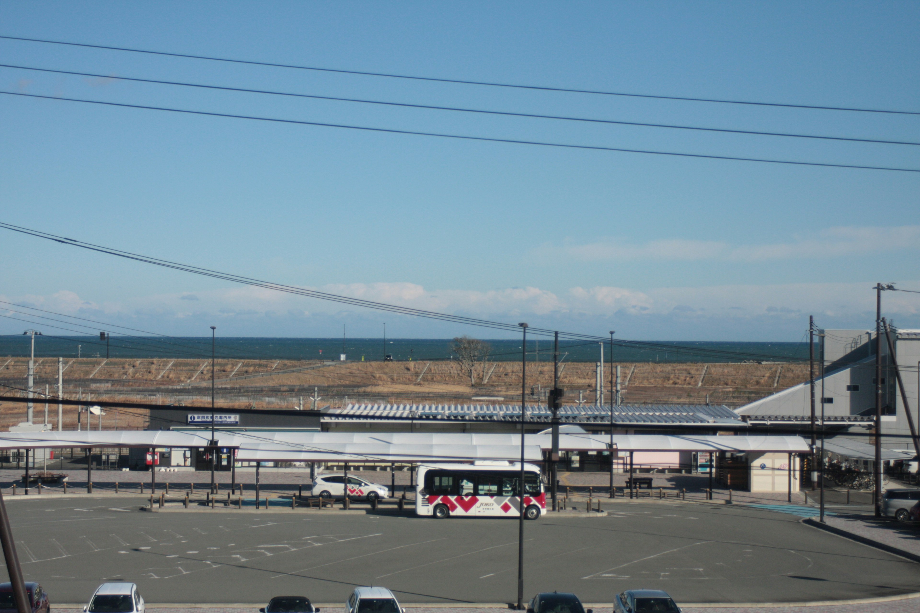 Blick auf das Meer und den blauen Himmel mit einem Bus und einem Parkplatz