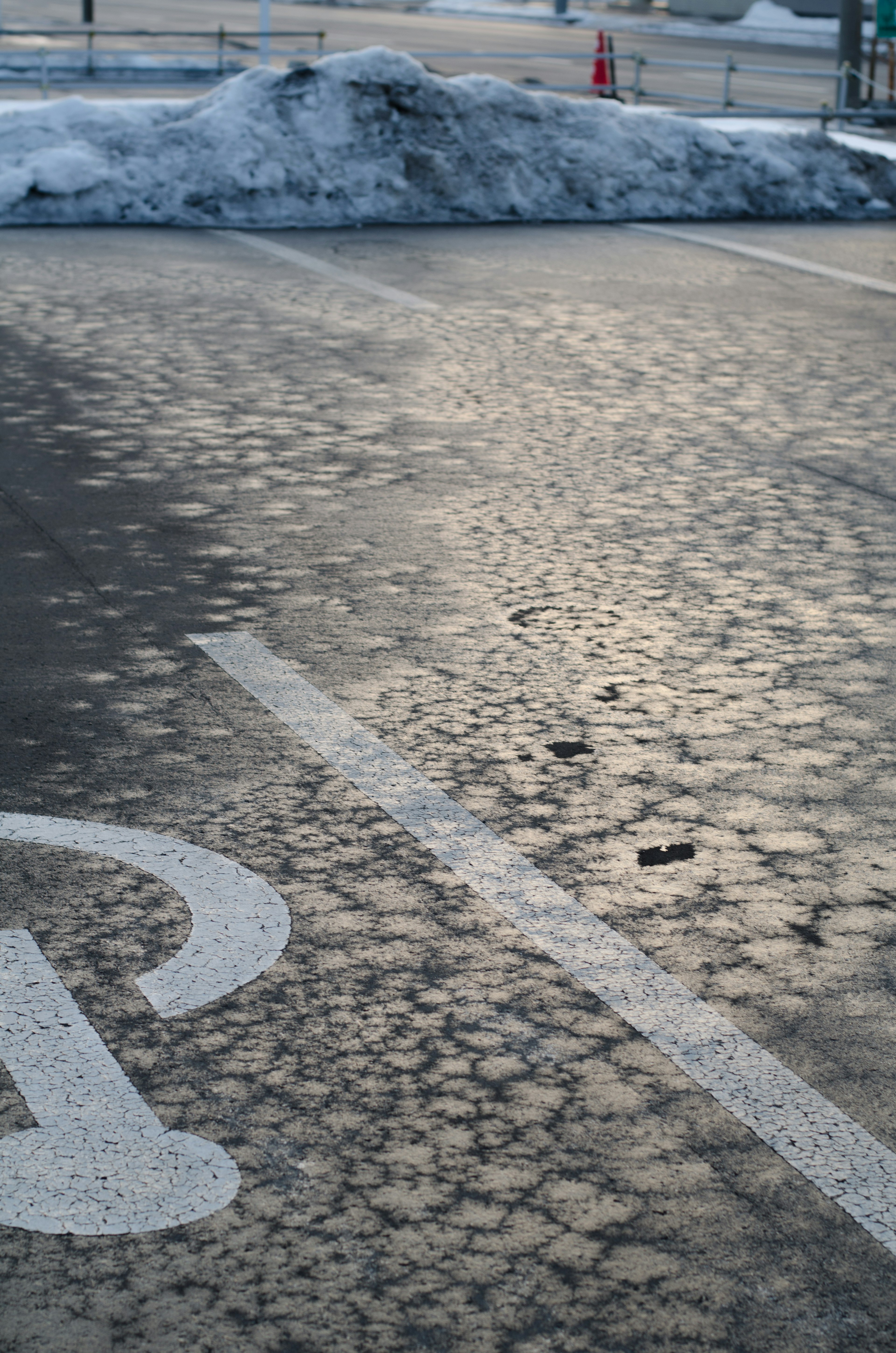 Paved parking lot surface reflecting light with snow remnants