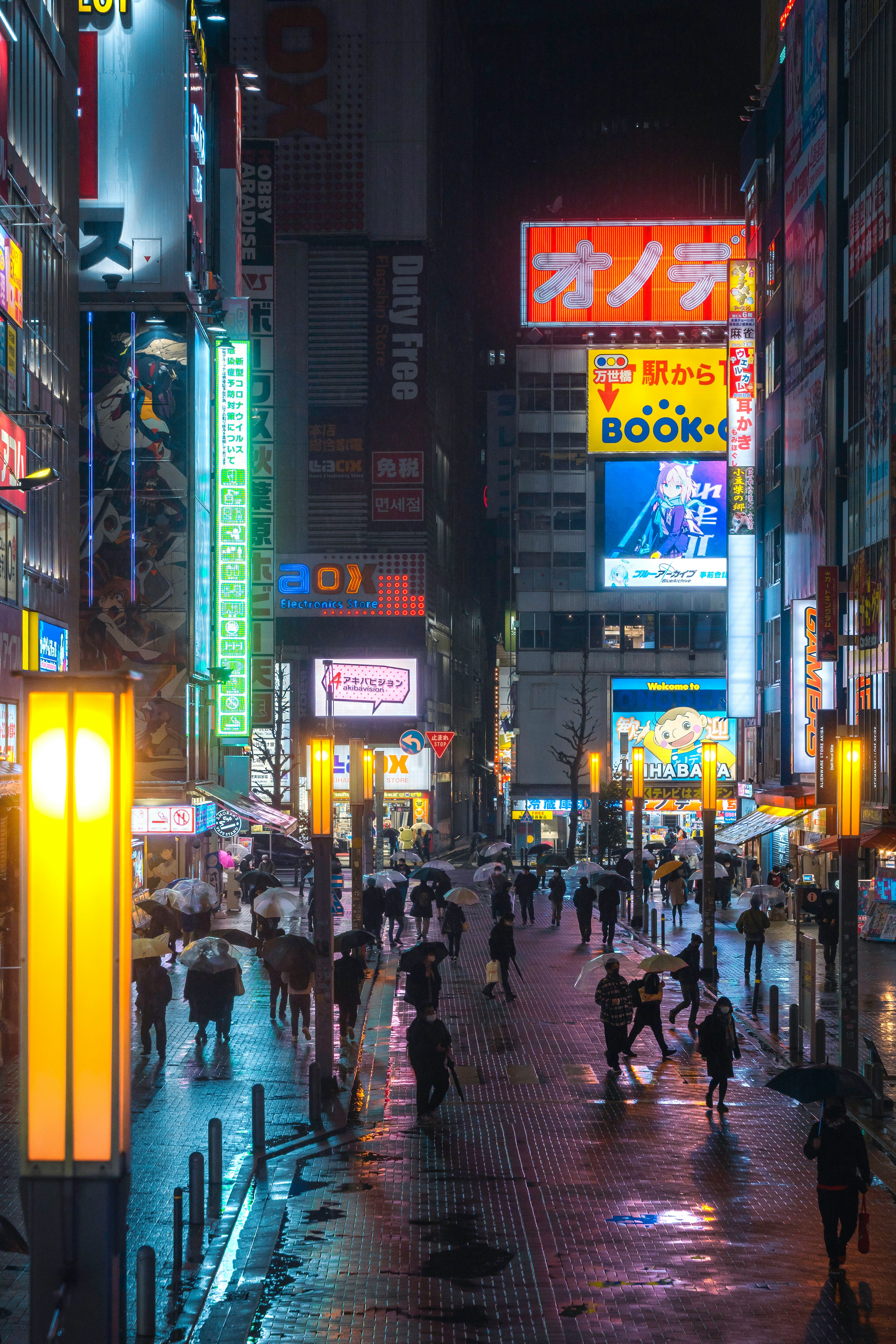 Night scene of a bustling city street with neon signs and wet pavement