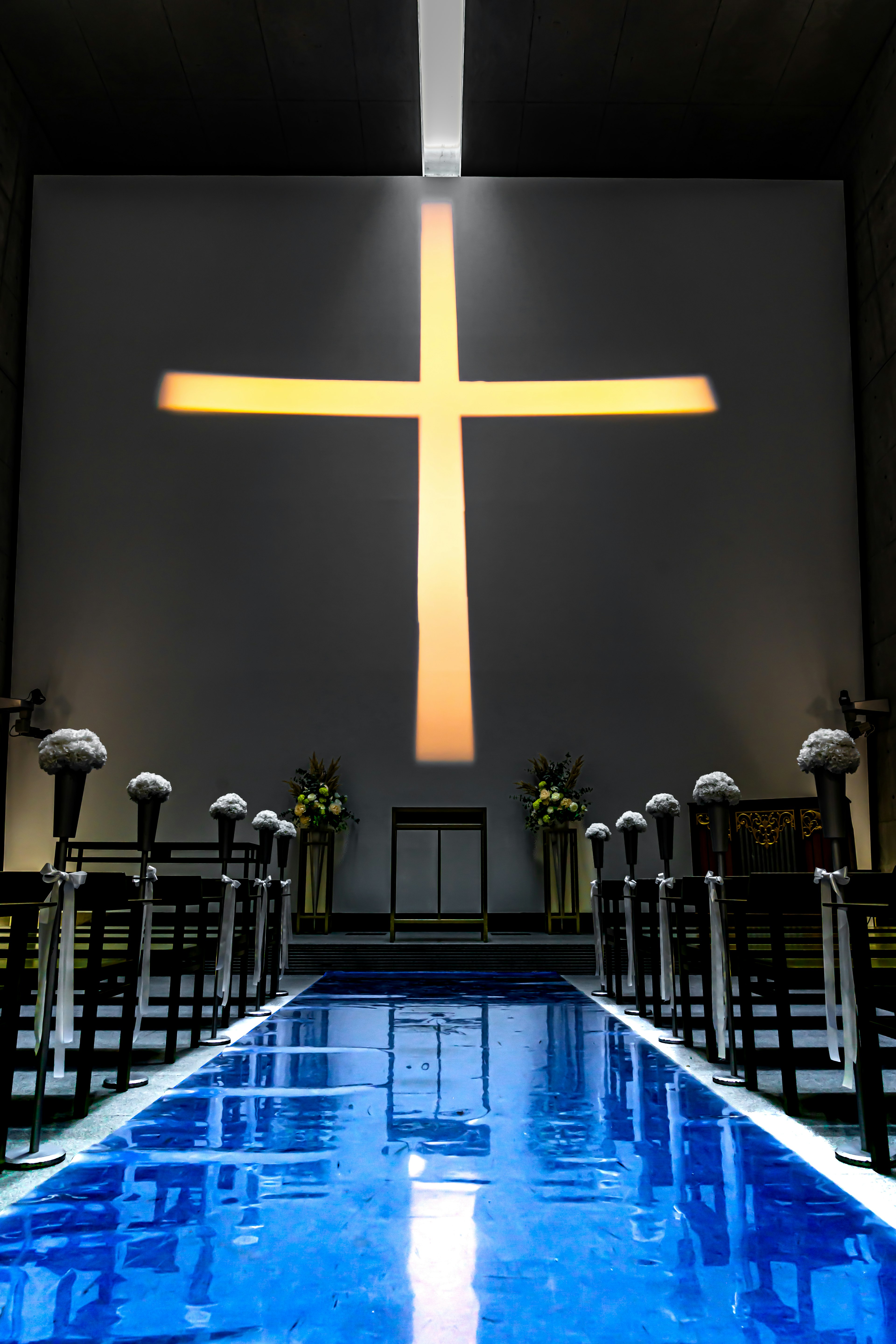 Inneneinrichtung einer Kirche mit einem blauen Weg und einem großen Kreuz im Hintergrund