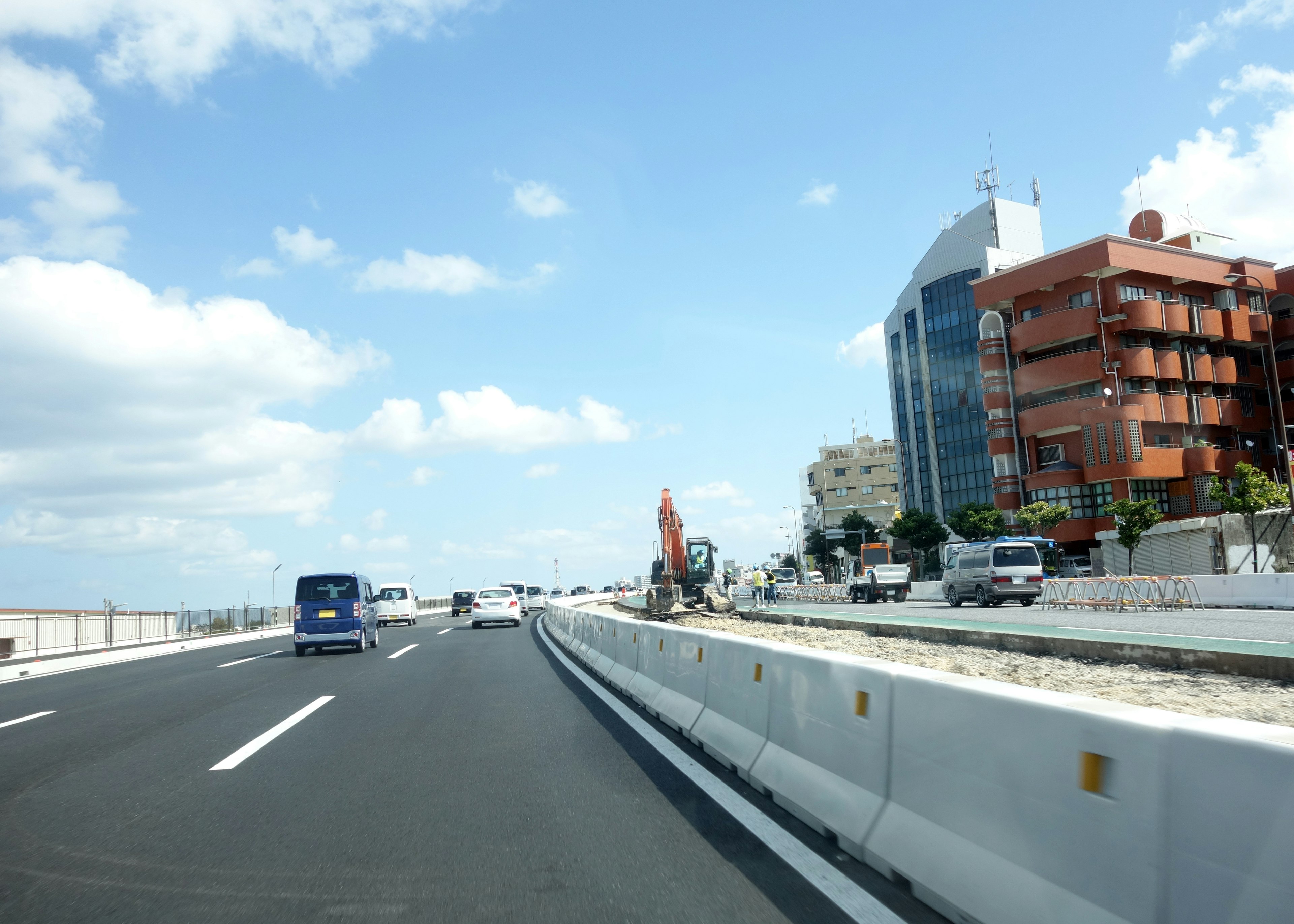 Pemandangan jalan tol dengan lanskap perkotaan di bawah langit biru