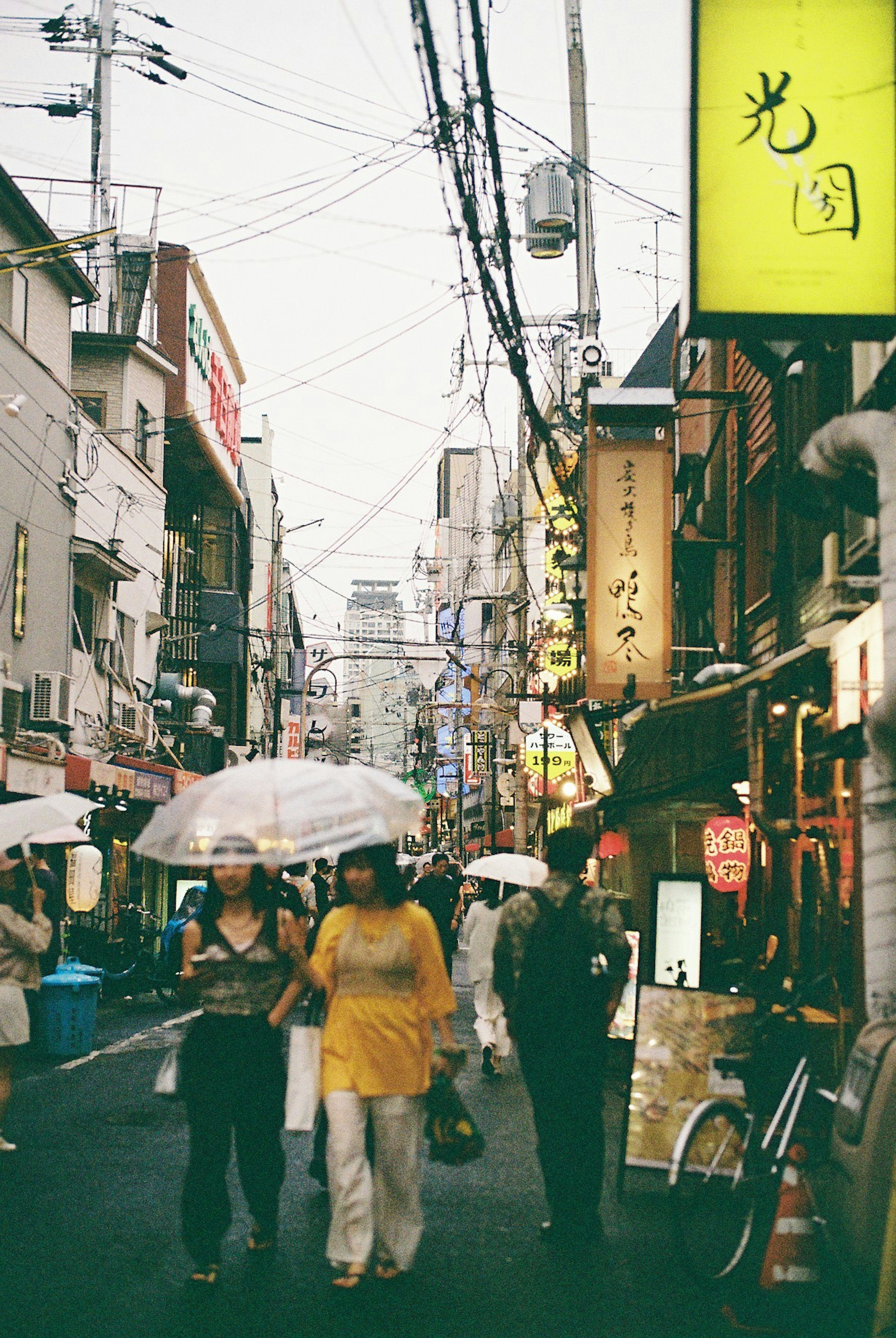 人々が傘をさして歩いている賑やかな街並みの風景