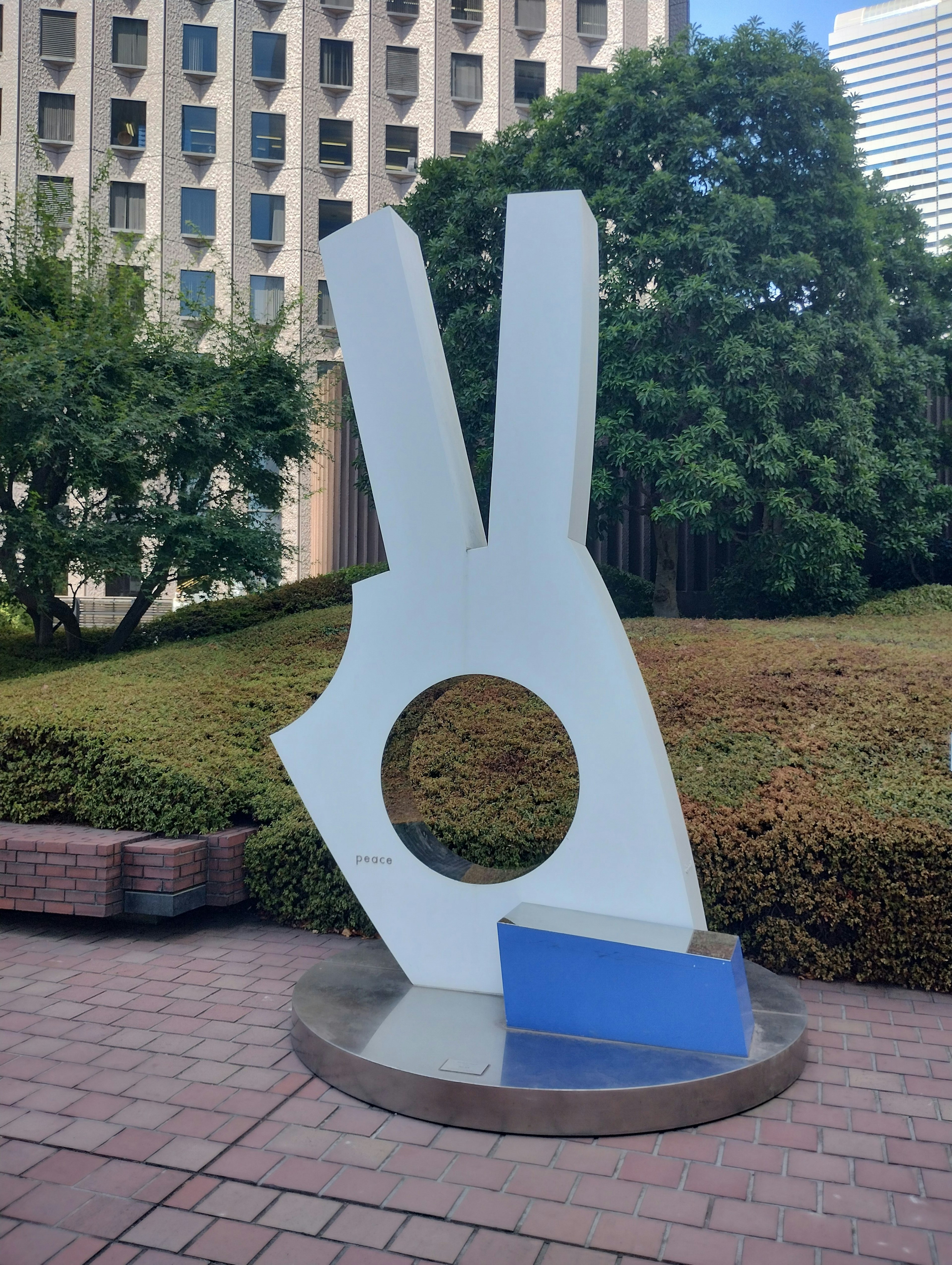 White hand-shaped sculpture with a blue base in a park