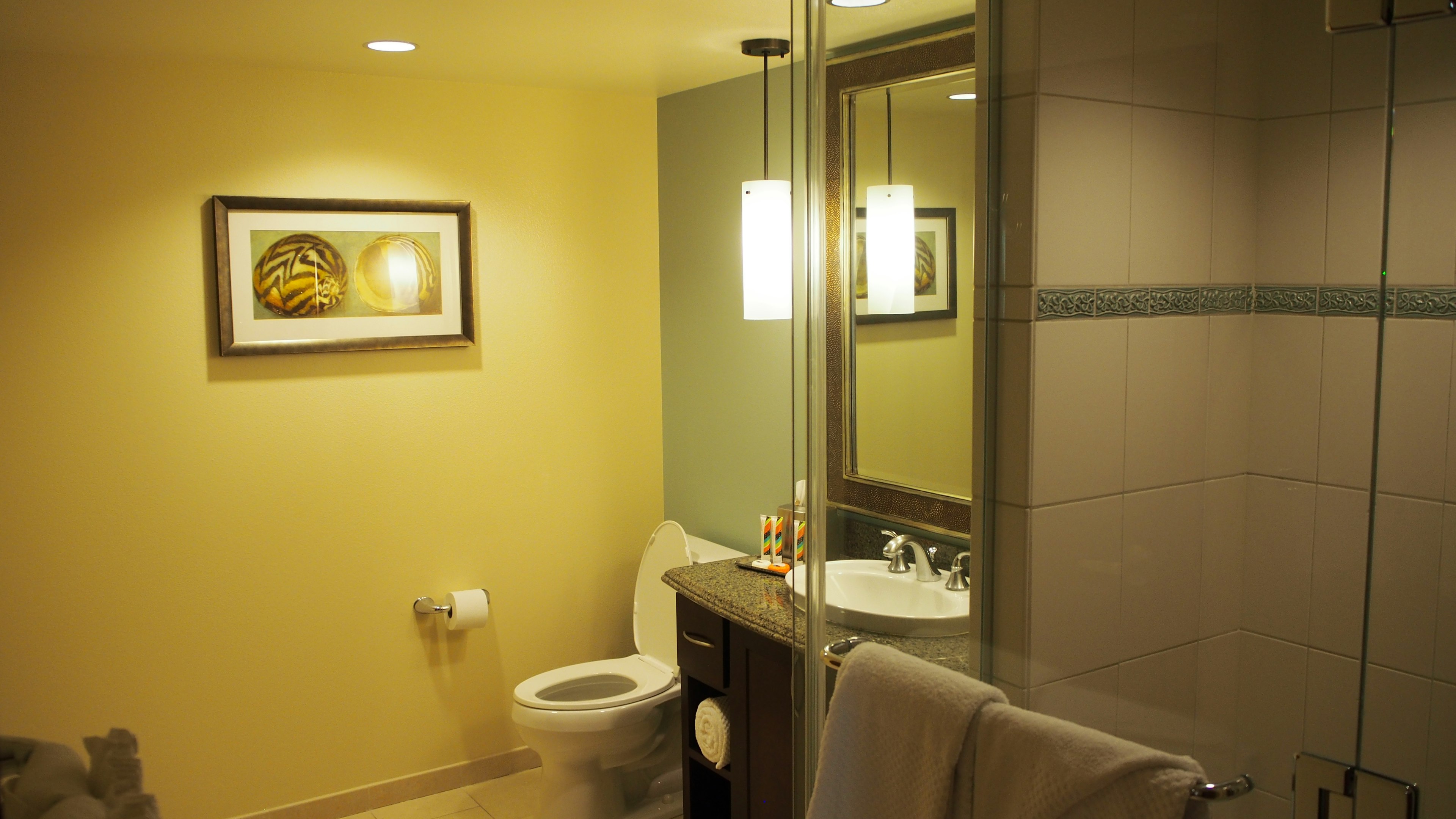 Salle de bain aux couleurs vives avec un lavabo et des toilettes reflétant dans un miroir