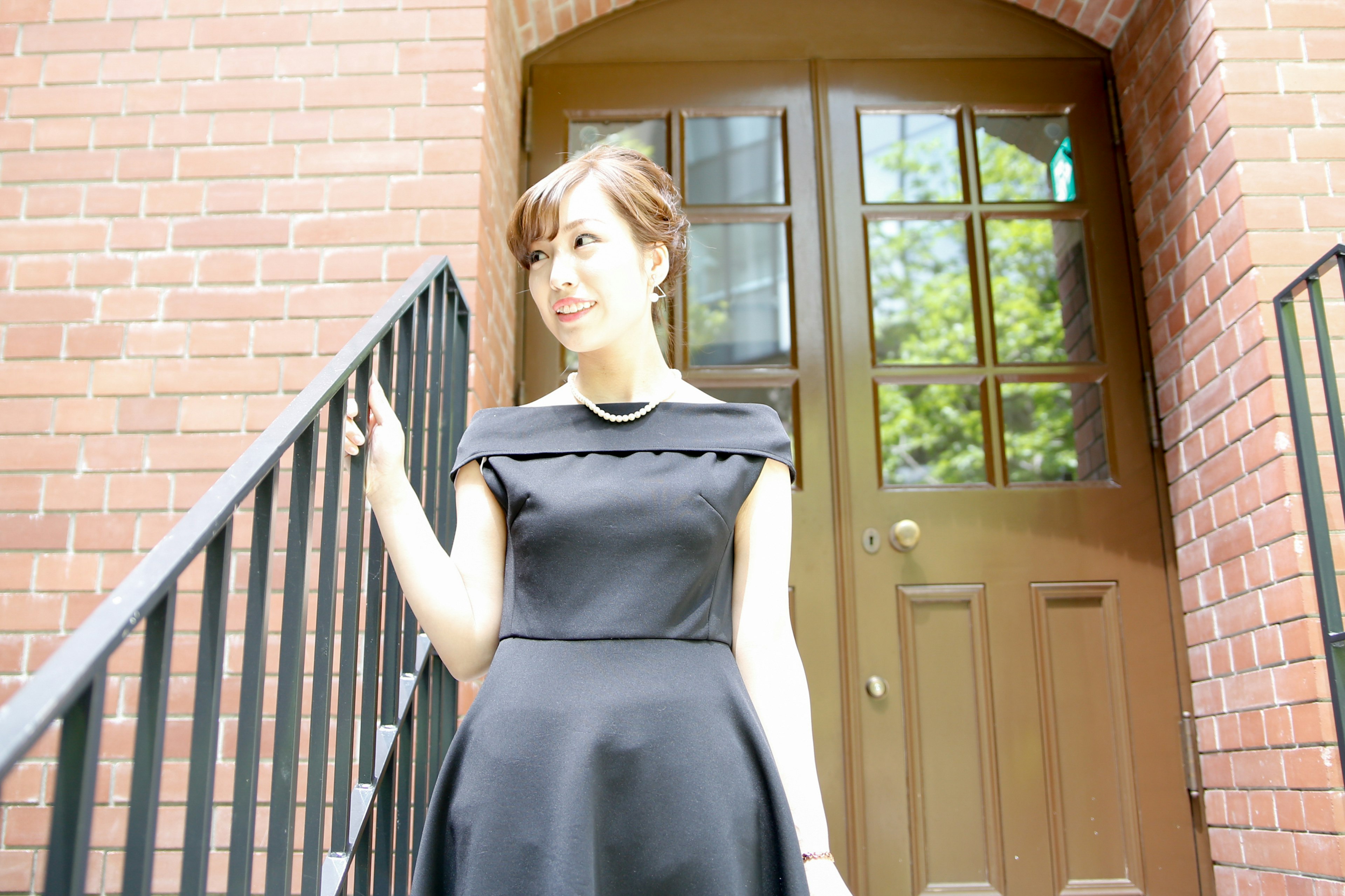 A woman in a black dress standing in front of a staircase