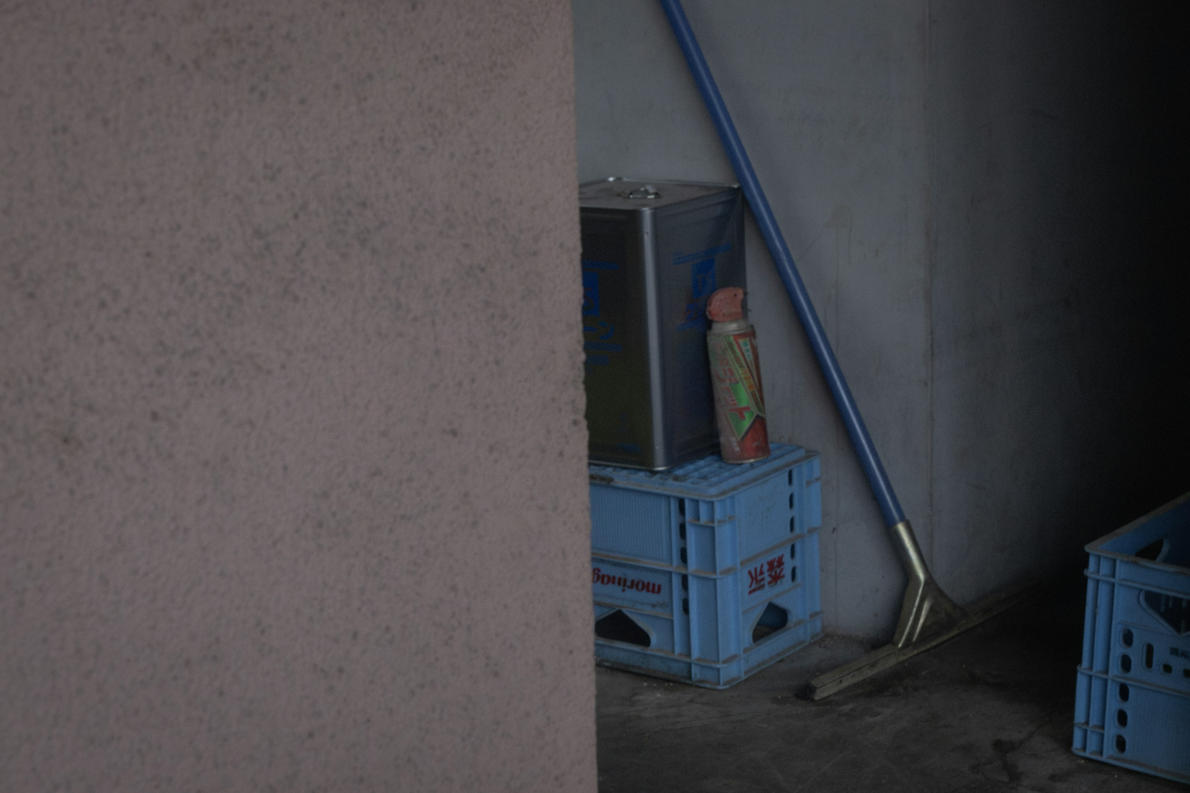 A dim space with a doll on top of a blue crate and cleaning tools