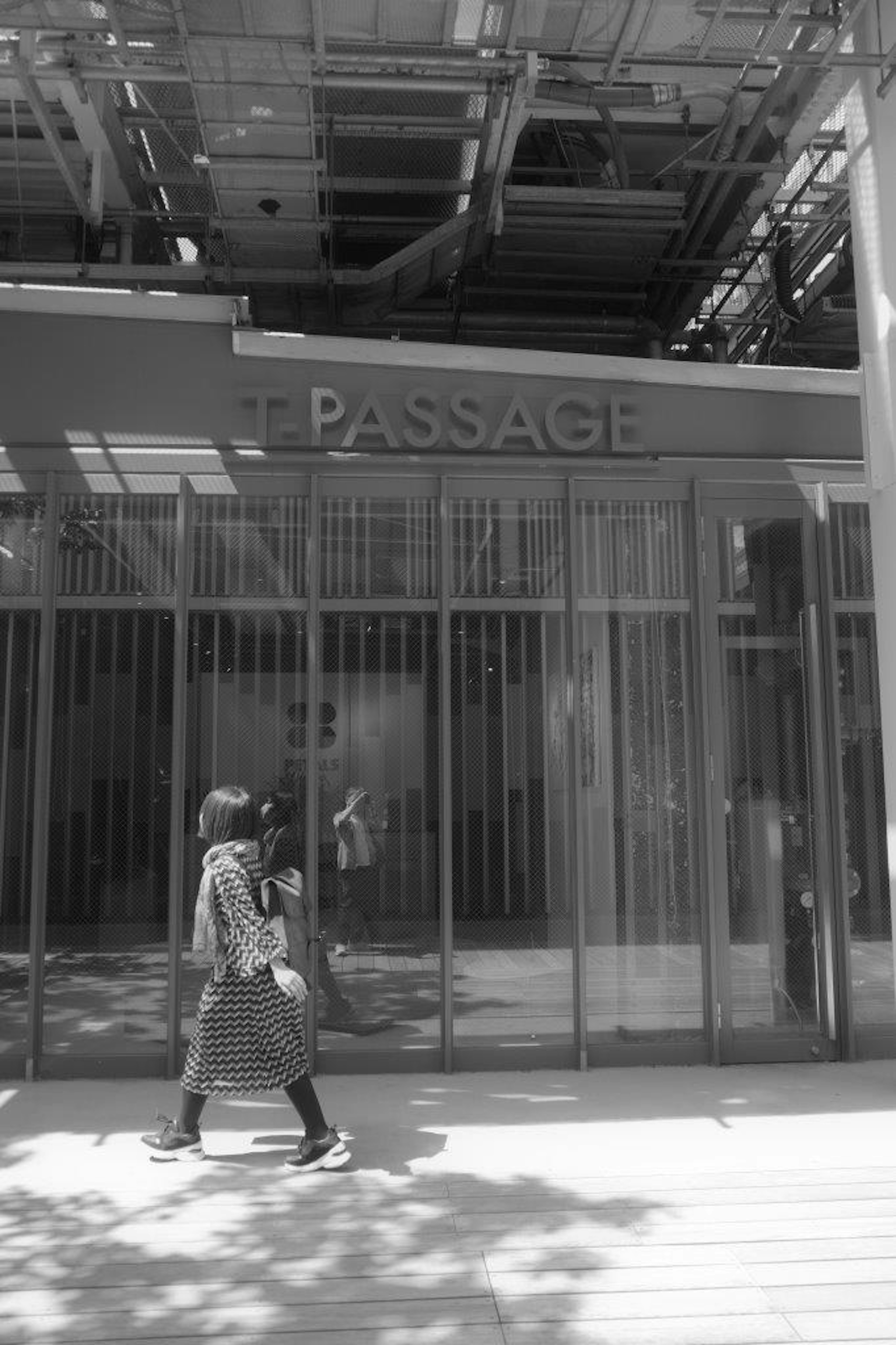 Femme marchant devant une porte vitrée étiquetée Passage