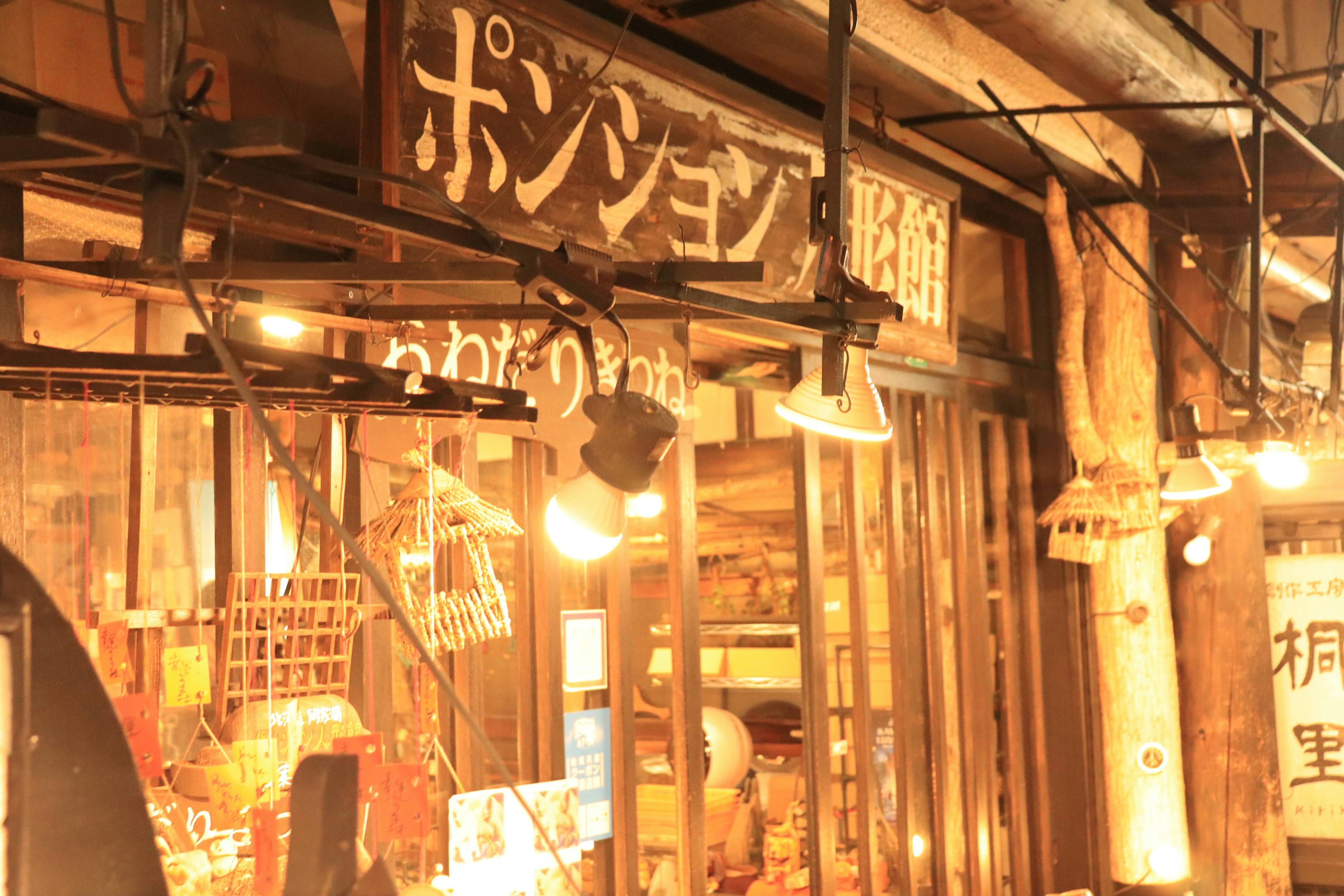 Exterior of a Japanese lodging with a wooden sign illuminated by warm light