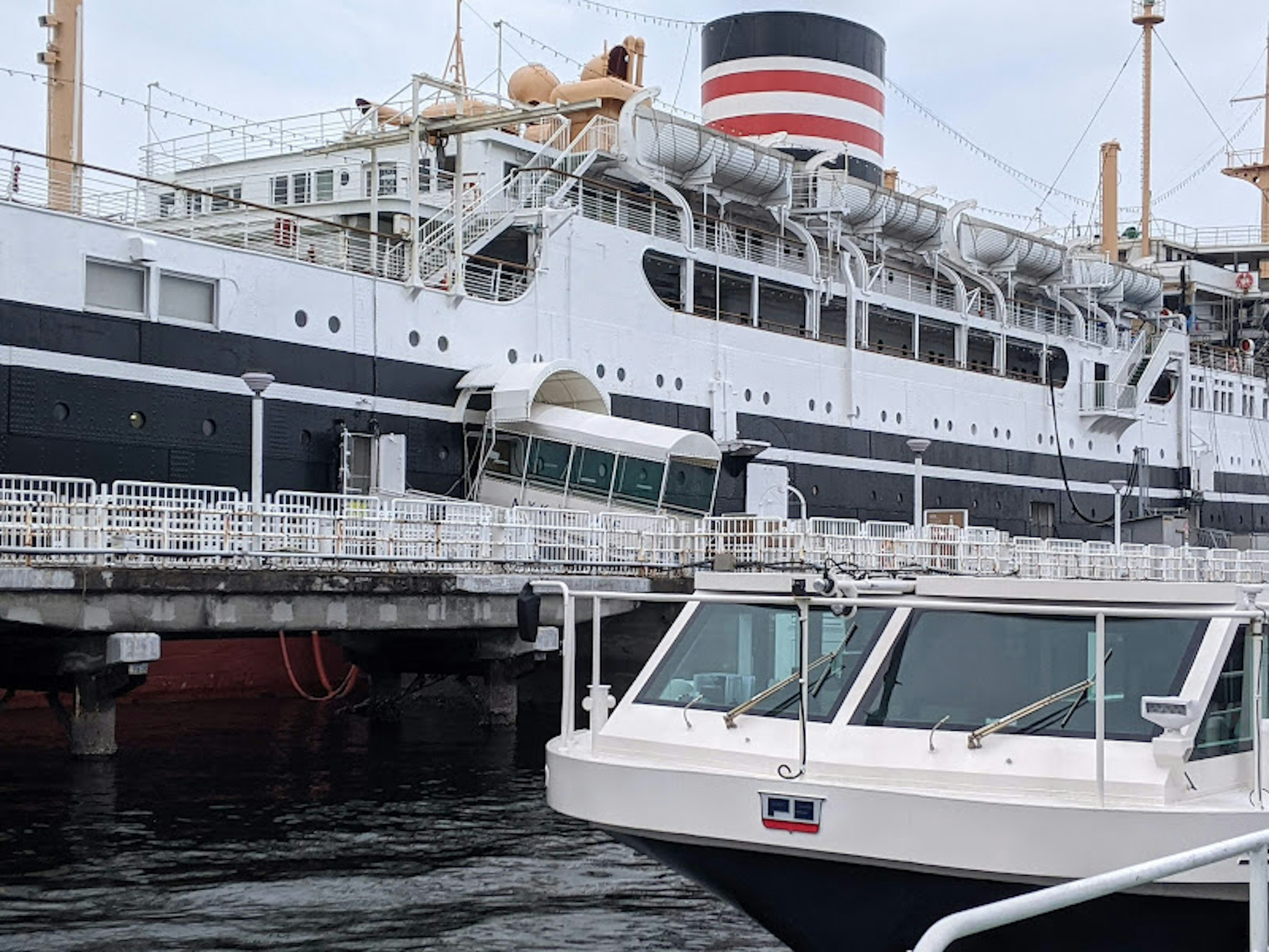 Luxury black and white ship docked at the harbor with a small boat in the foreground