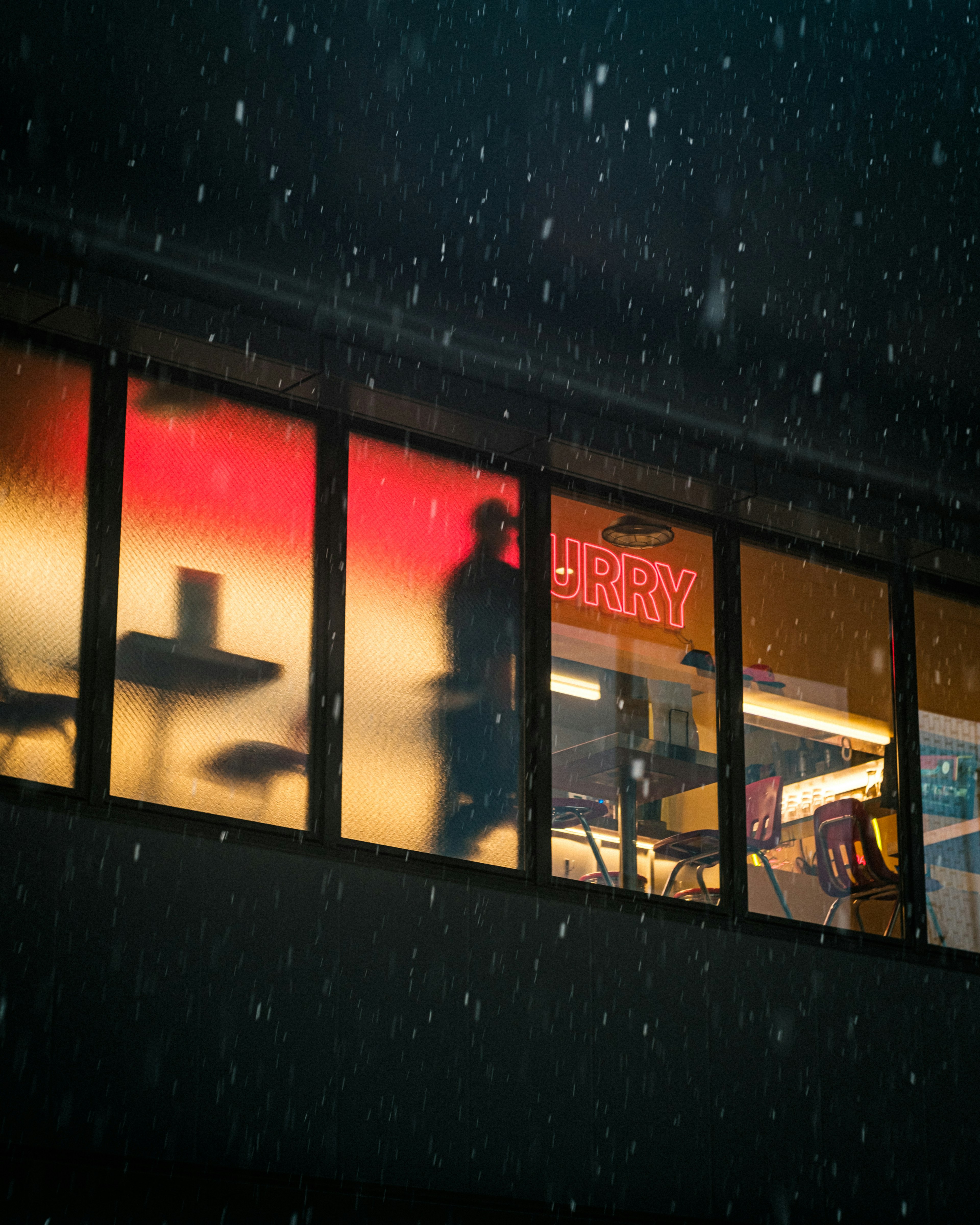 Silhouette einer Person hinter einem Fenster mit bunten Schildern im Schnee