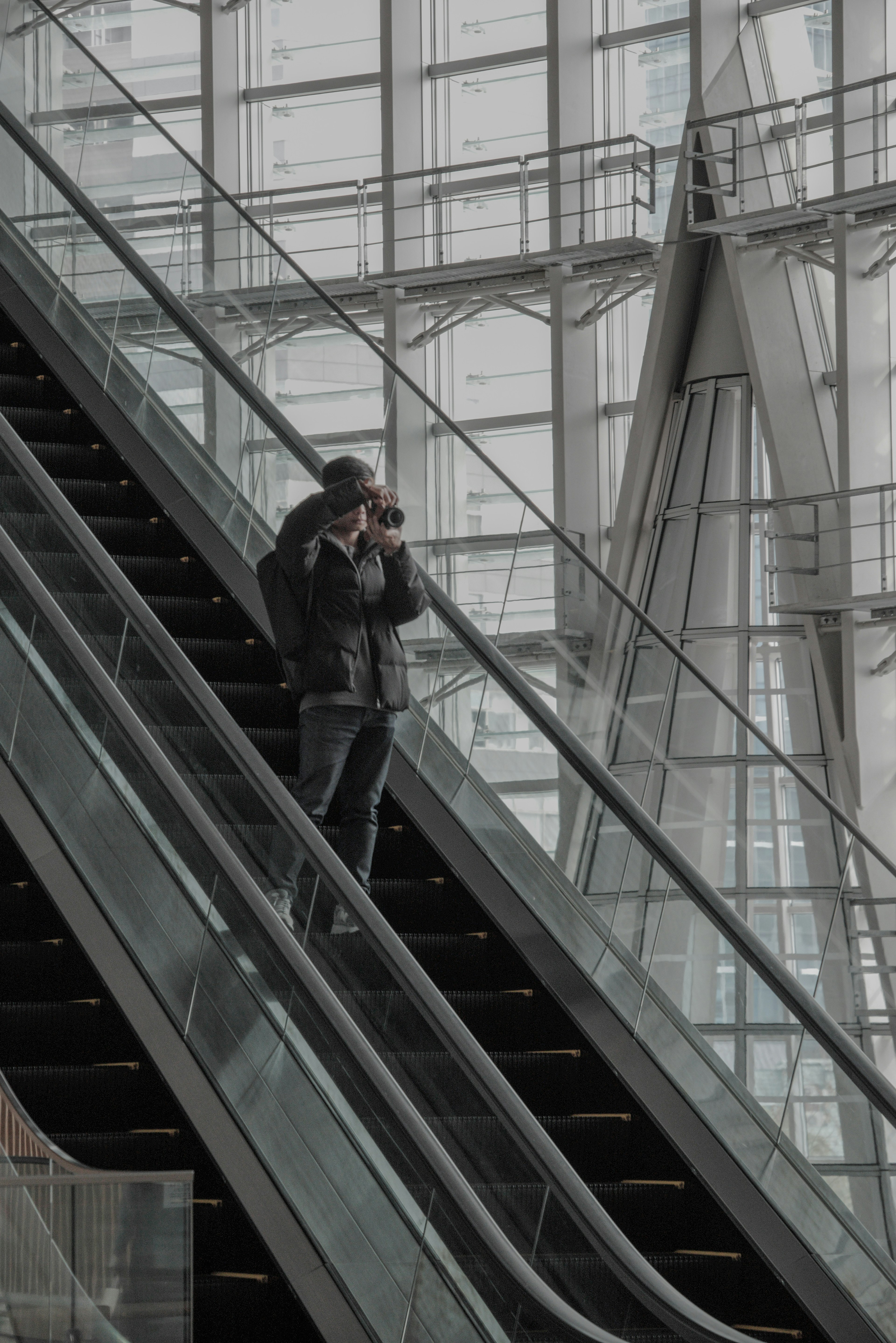 Person steht auf einer Rolltreppe in einem Glasgebäude