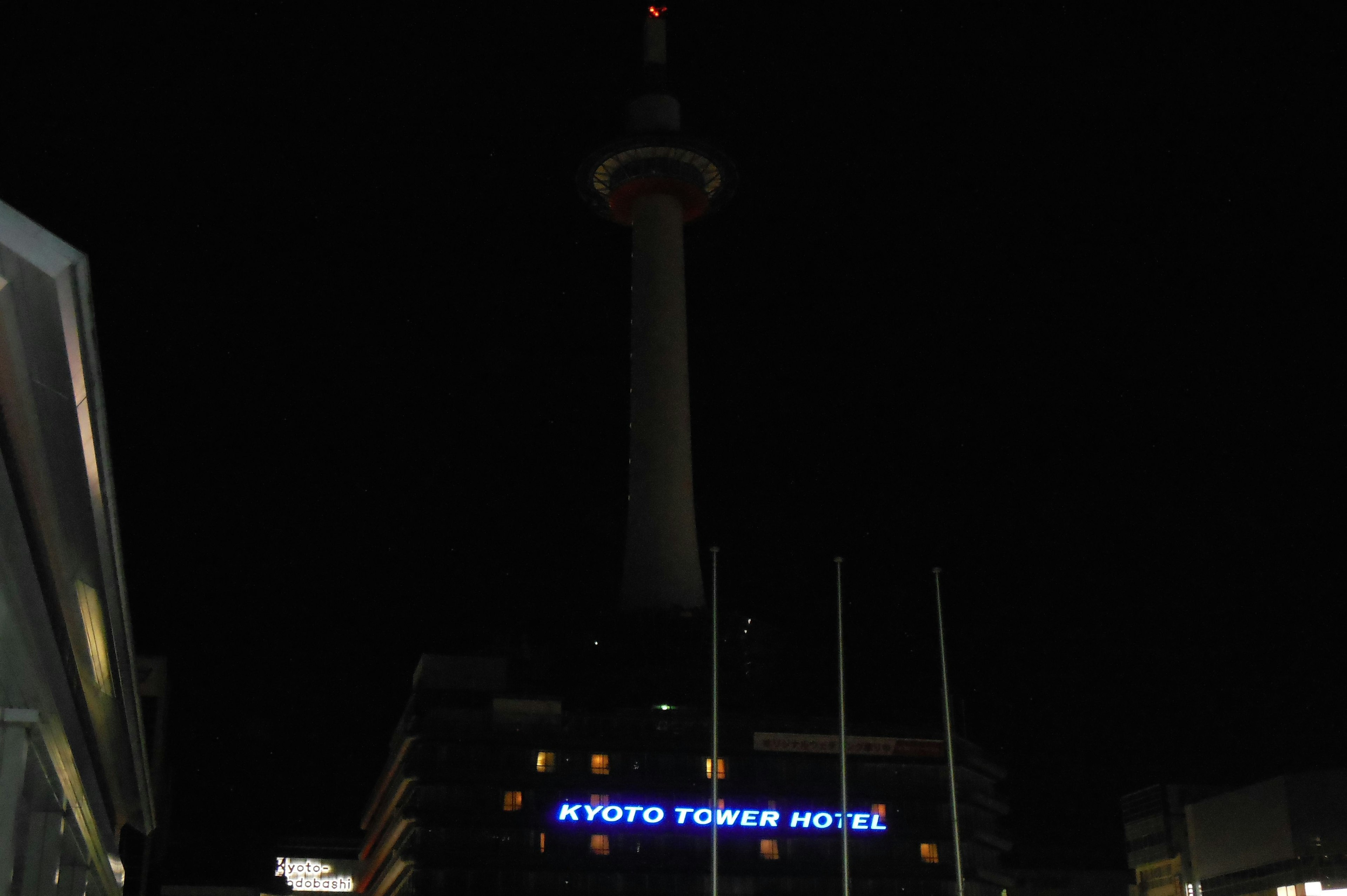 Torre de Kyoto iluminada por la noche con edificios circundantes