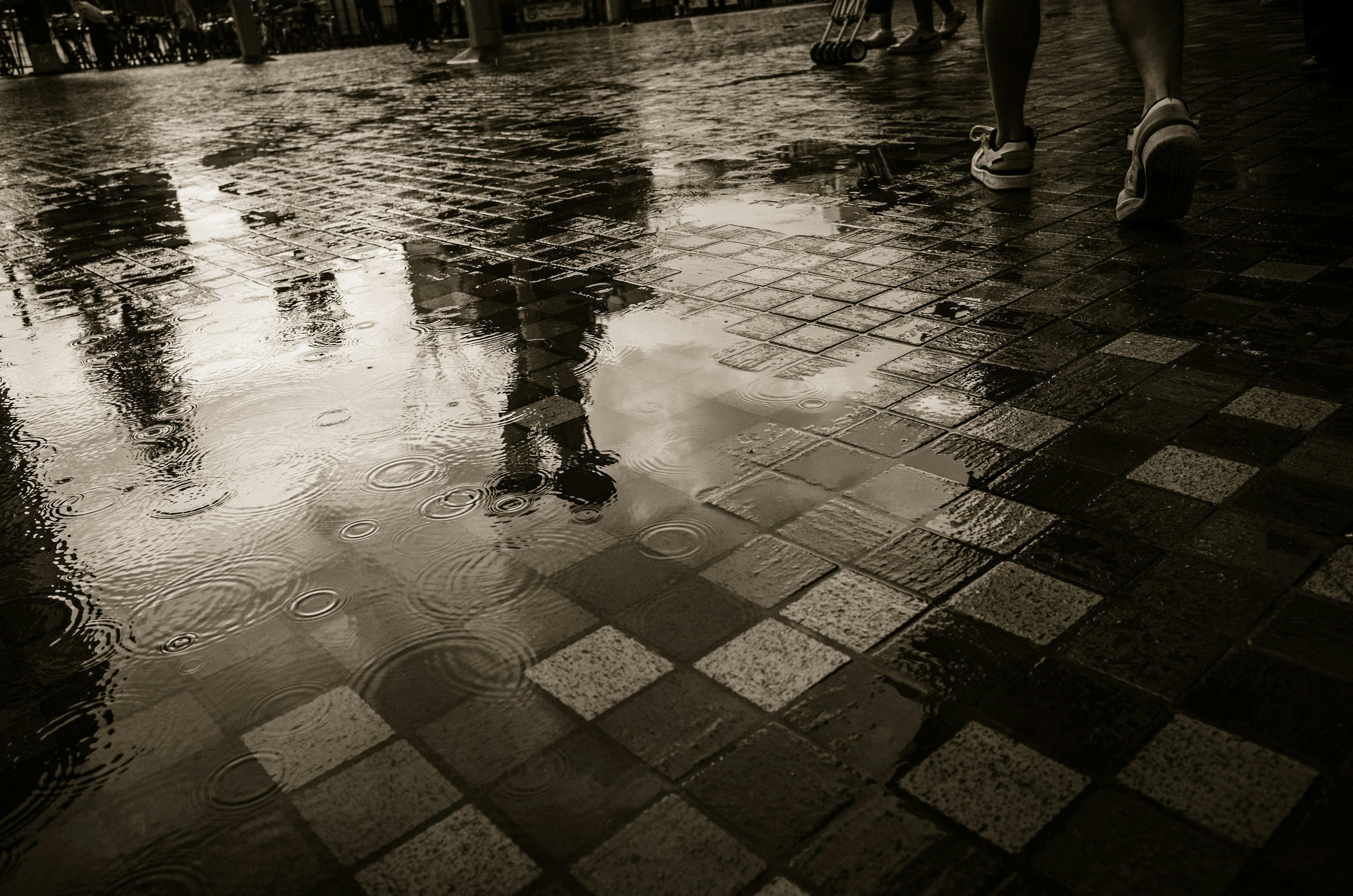 Füße auf einer regennassen Kopfsteinpflasteroberfläche, die die Umgebung reflektiert