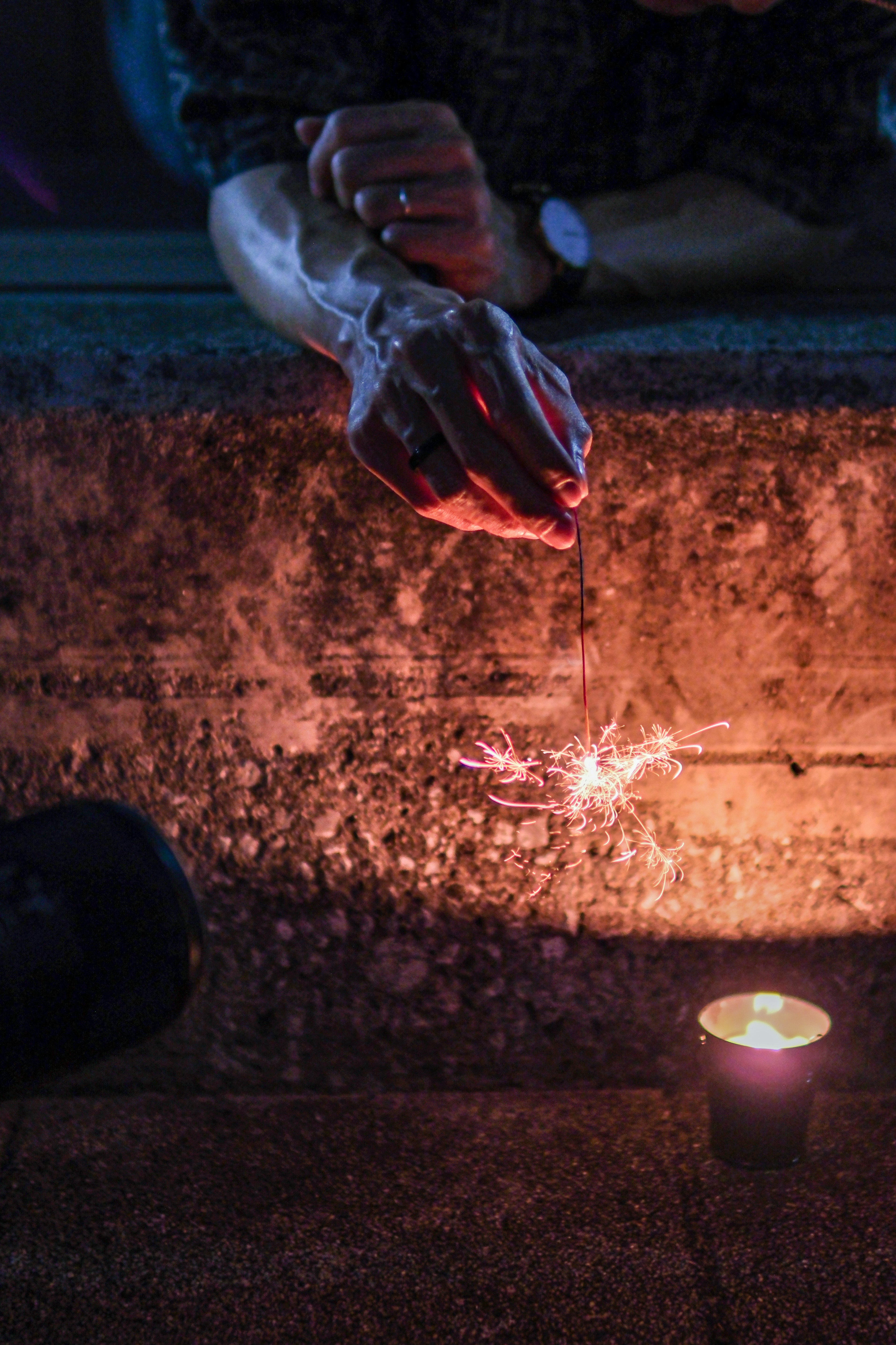 A hand creating sparks near a candle's warm glow