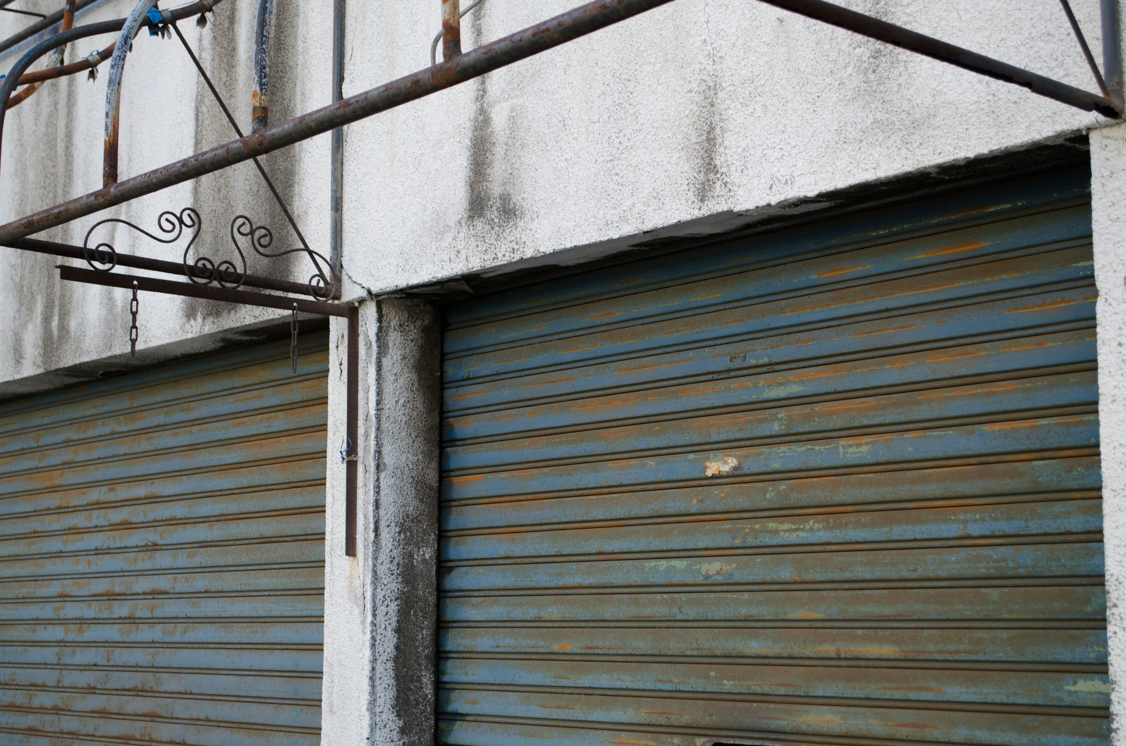 Closed storefront with blue rolling shutters and rusty metal frame