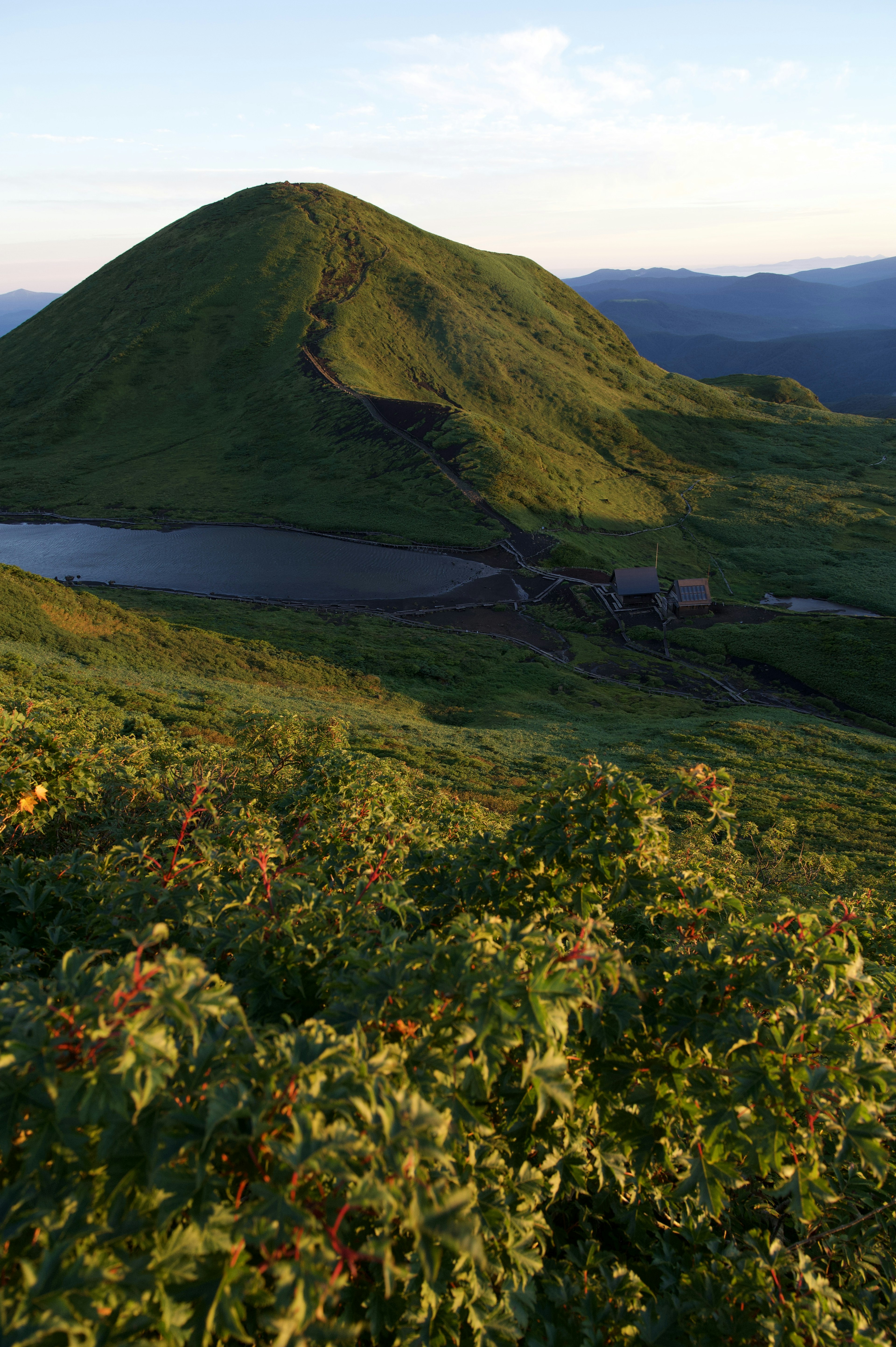 Vue pittoresque d'une colline verte et d'un lac sous un ciel clair