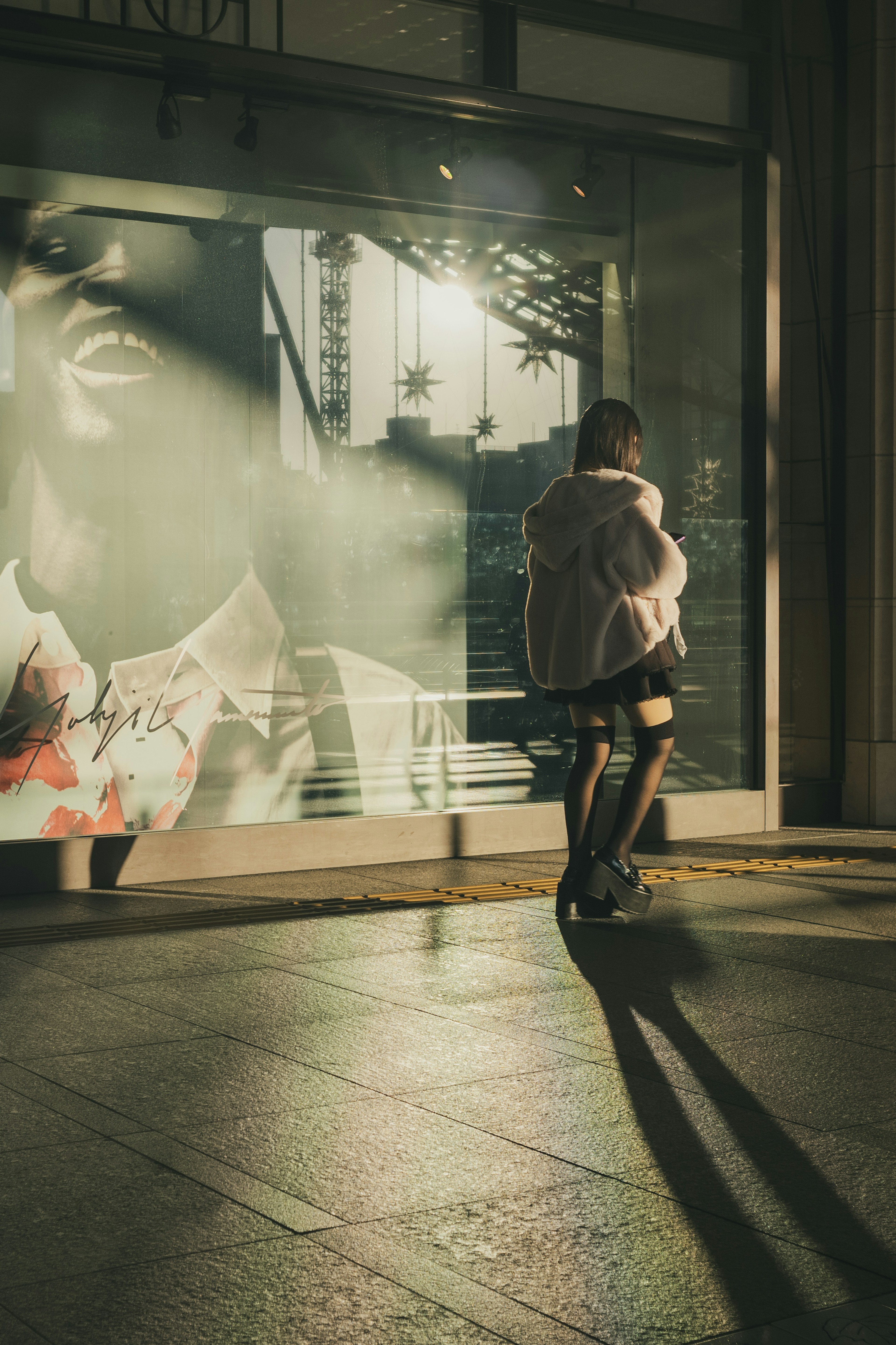 A person standing in front of glass with a large poster in the background