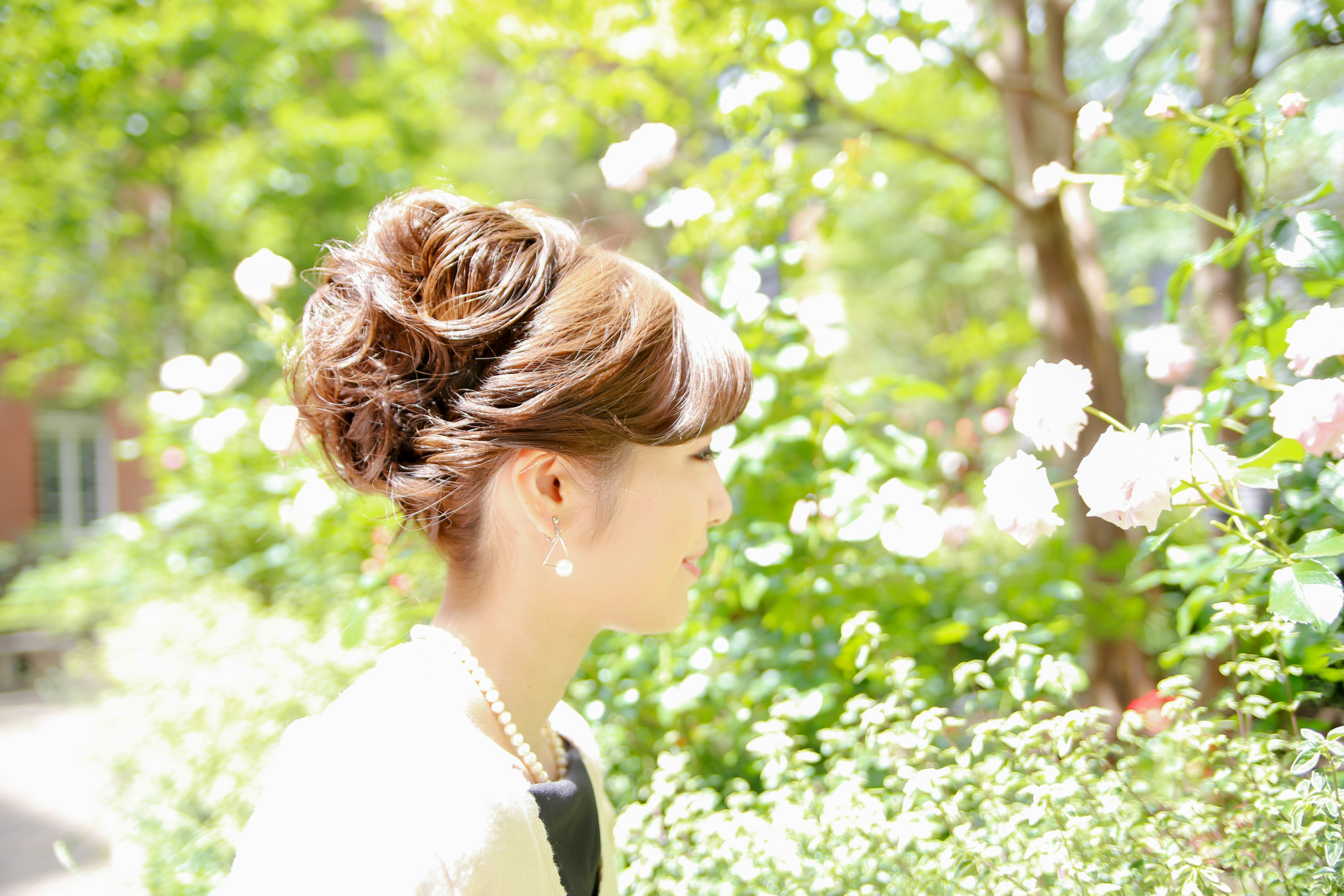 A young woman with an elegant hairstyle standing by blooming flowers