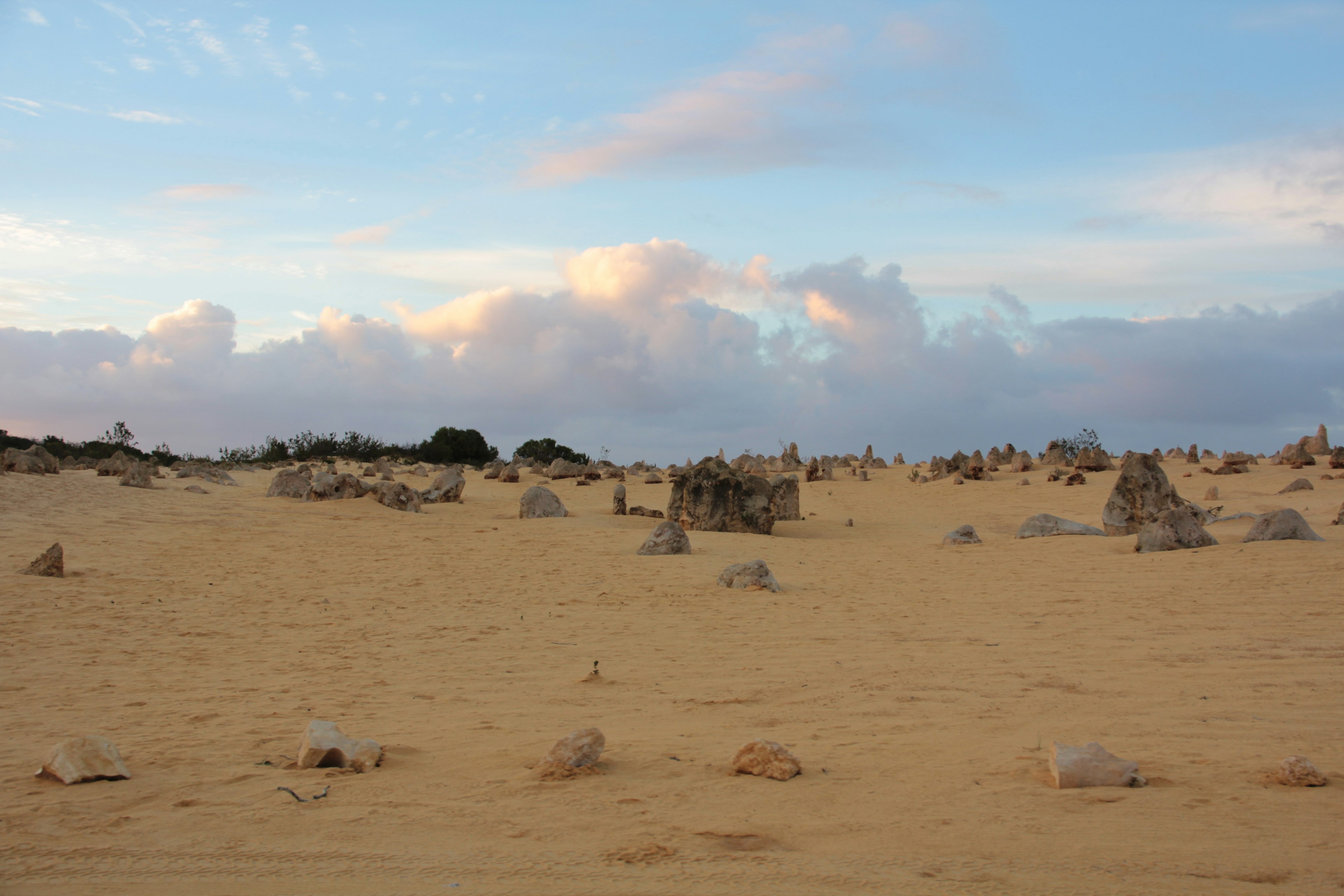 Paysage désertique vaste avec des rochers éparpillés et des nuages doux dans le ciel