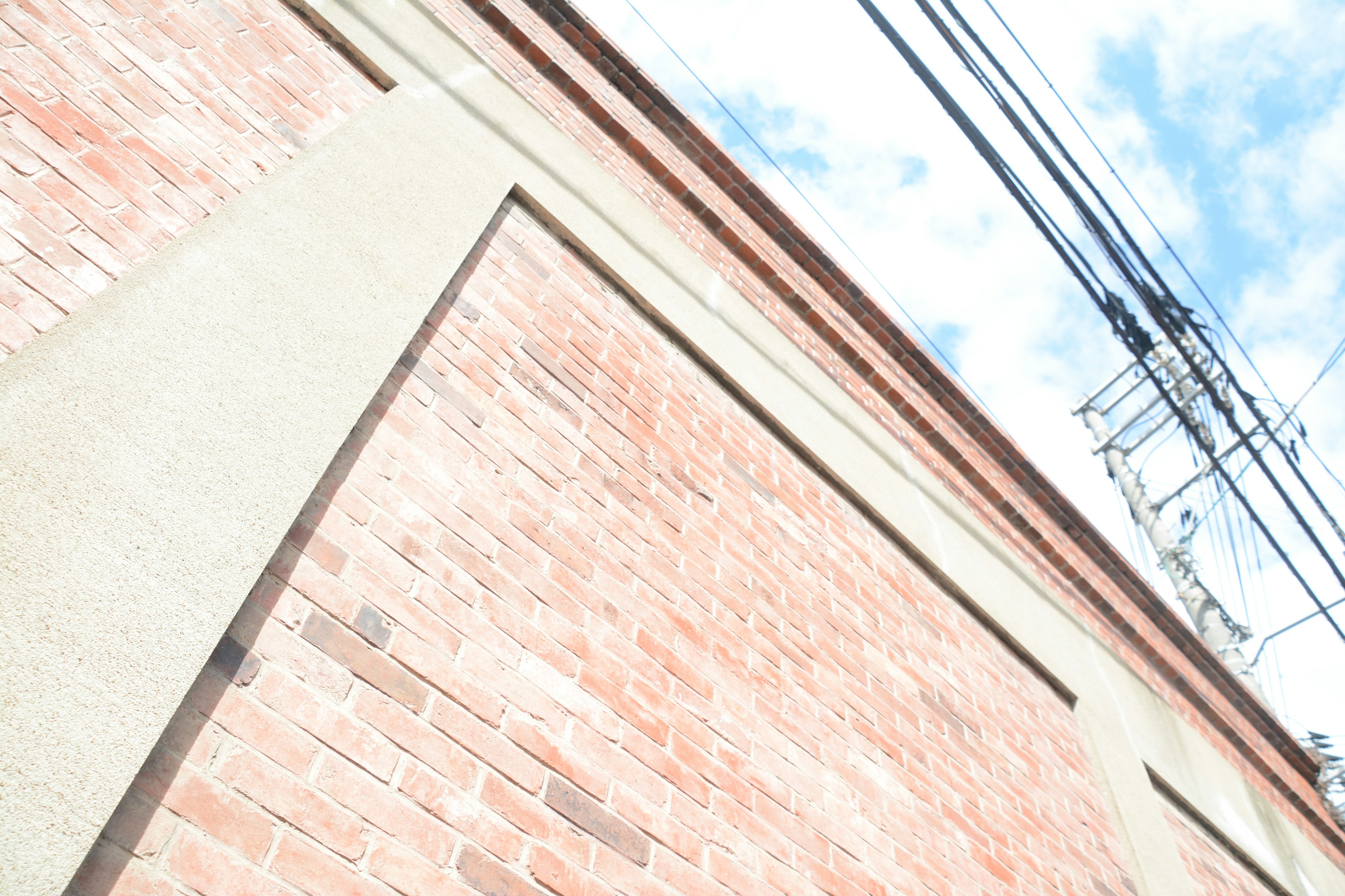 Image featuring a textured brick wall against a bright blue sky