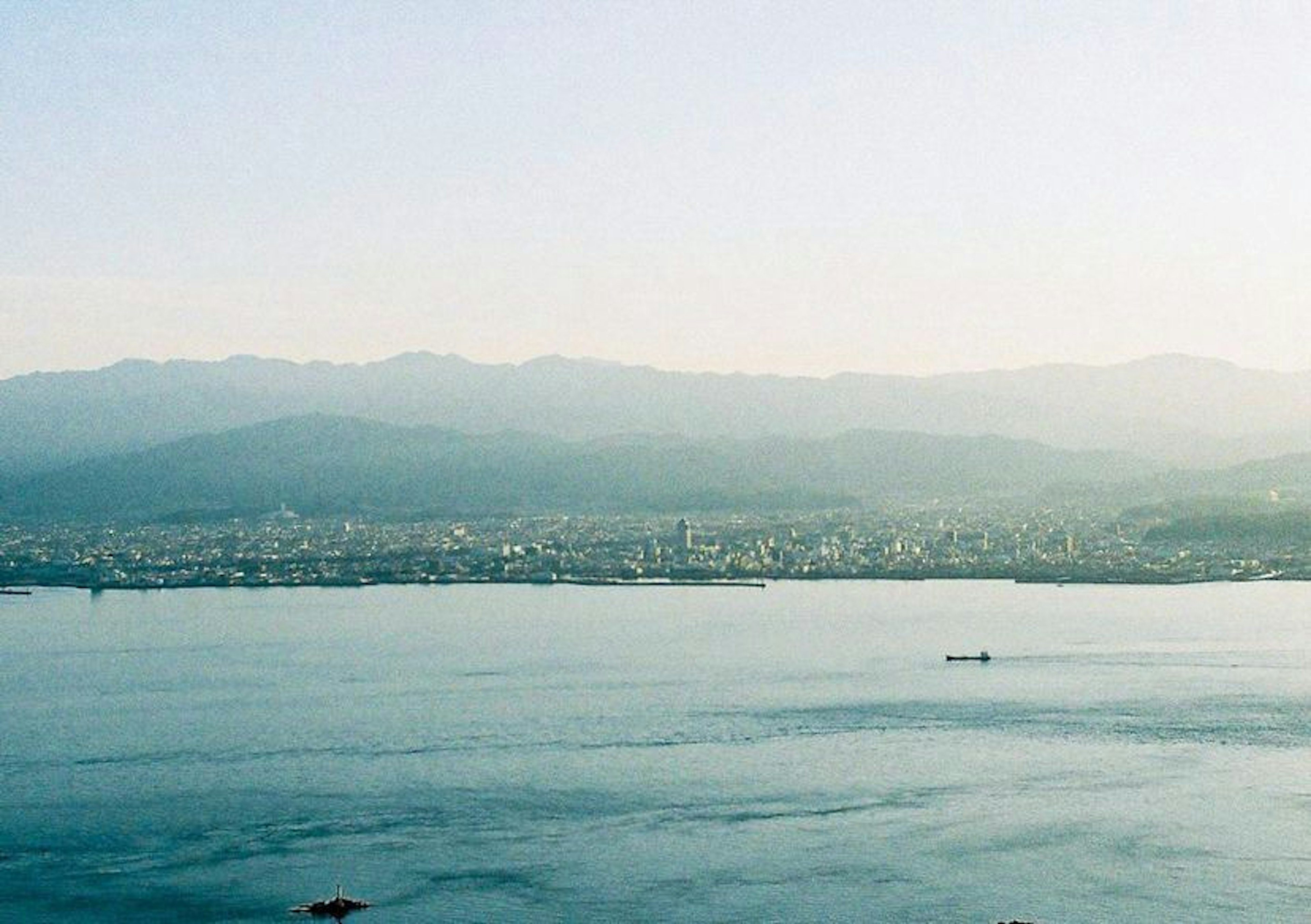 城市天际线，背景是蓝色海洋和山脉