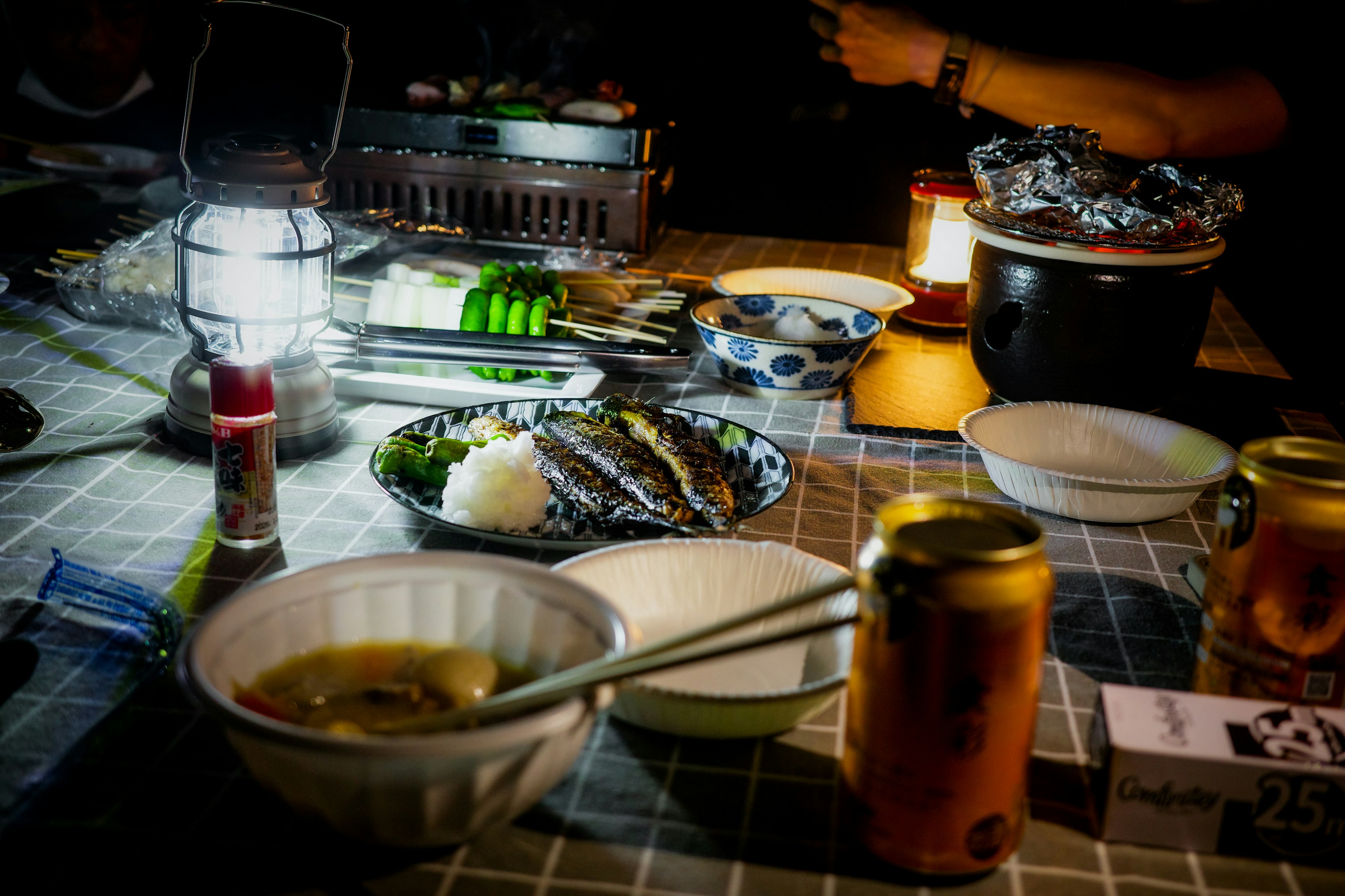 Scène de dîner nocturne avec des plats de poisson et du riz illuminés par la lumière d'une lanterne