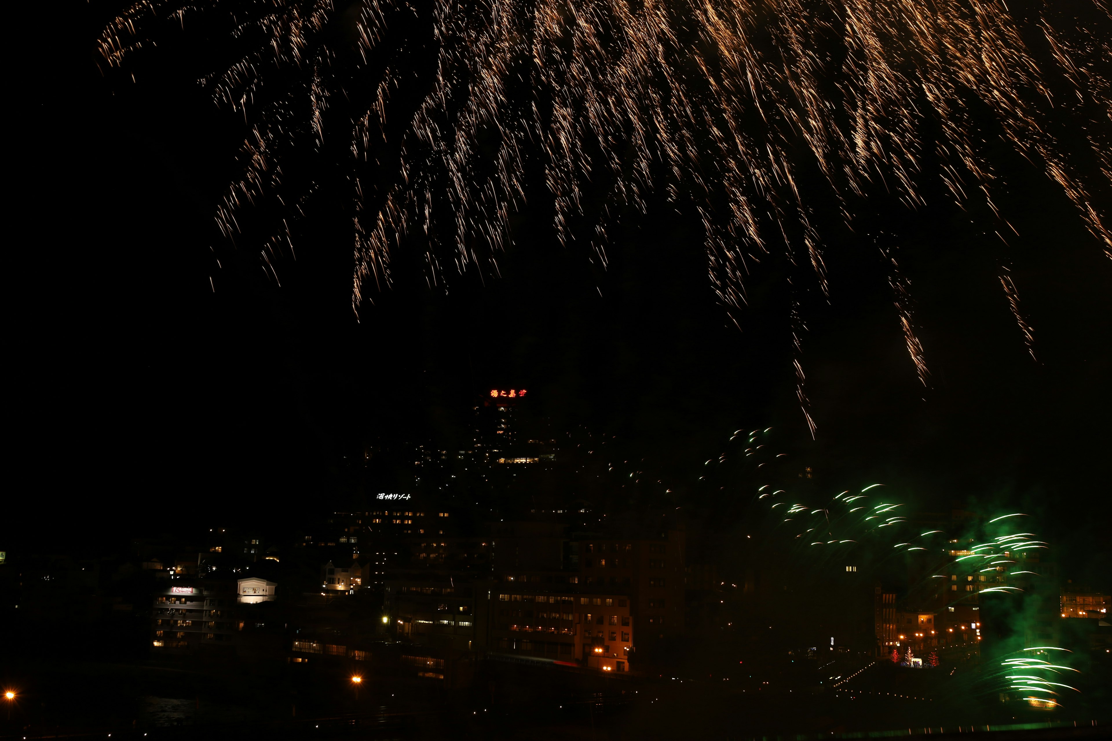 Los fuegos artificiales estallan en el cielo nocturno sobre el horizonte de una ciudad