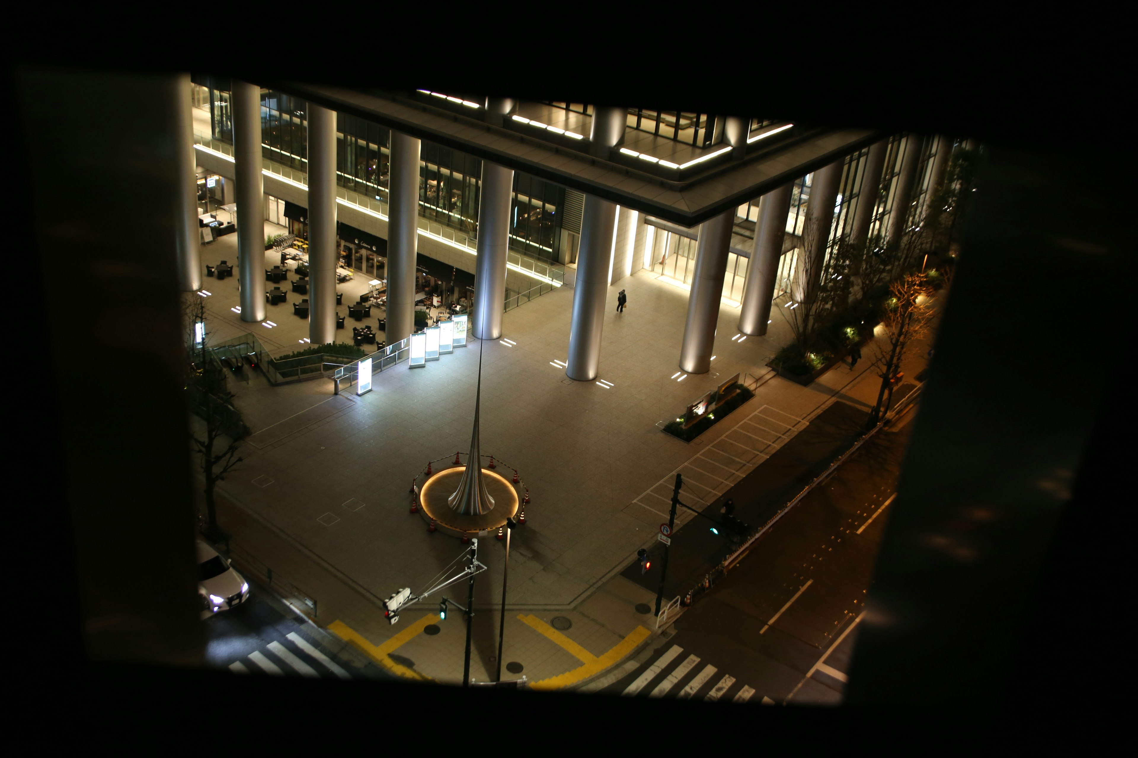 Vue d'un bâtiment moderne et d'une place la nuit avec des colonnes illuminées