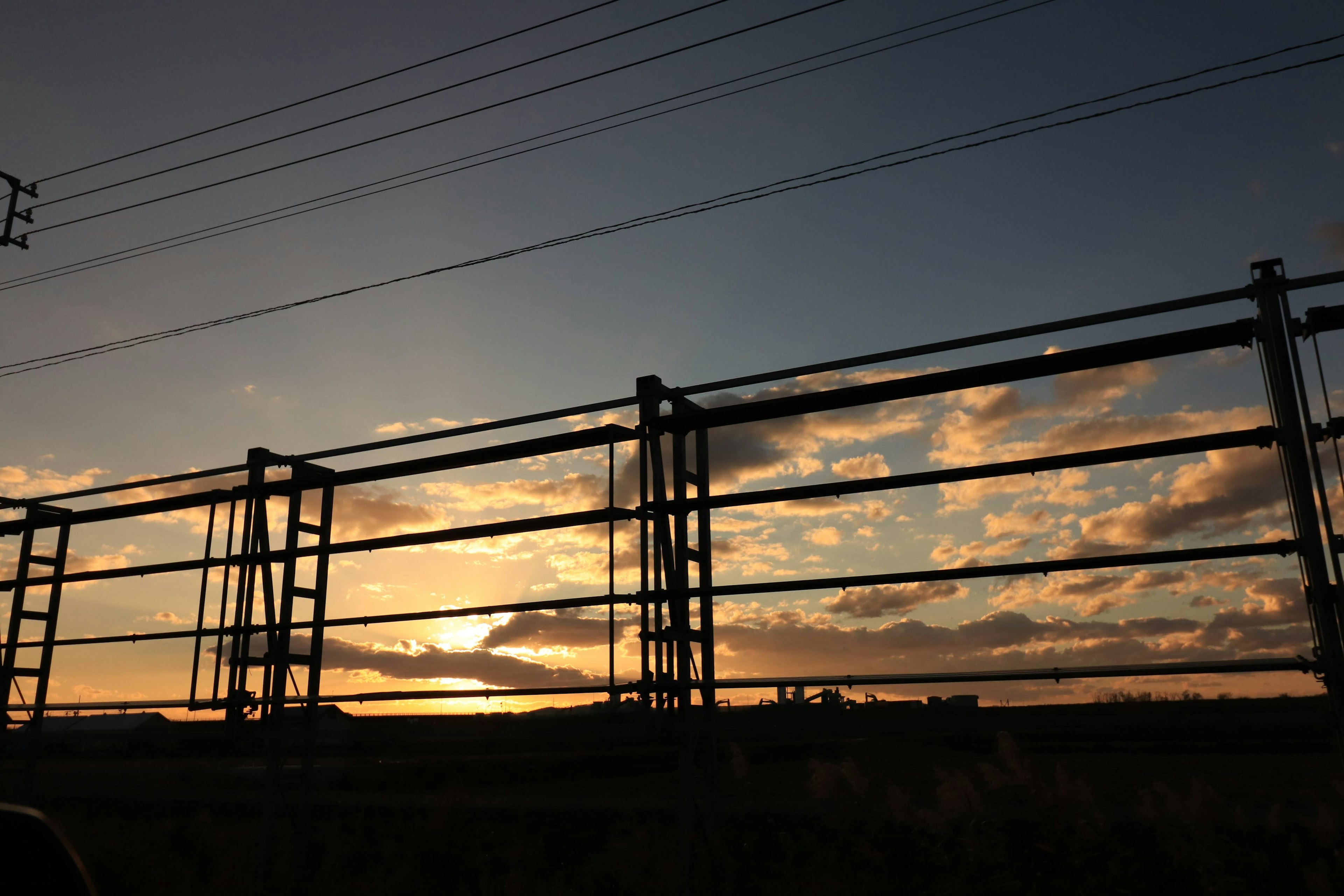 Silhouette of a metal fence against a sunset