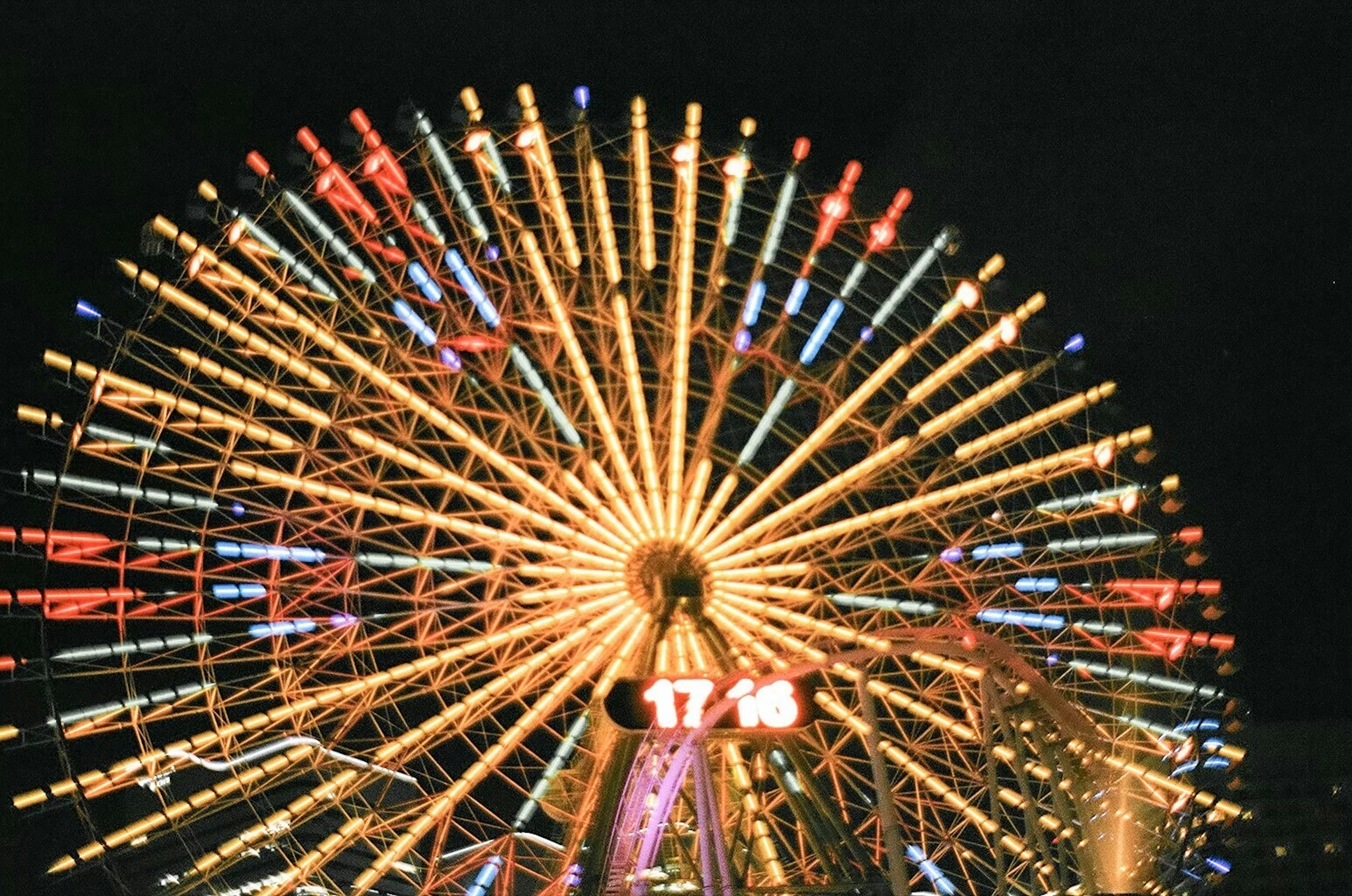 Colorful illuminated Ferris wheel against the night sky