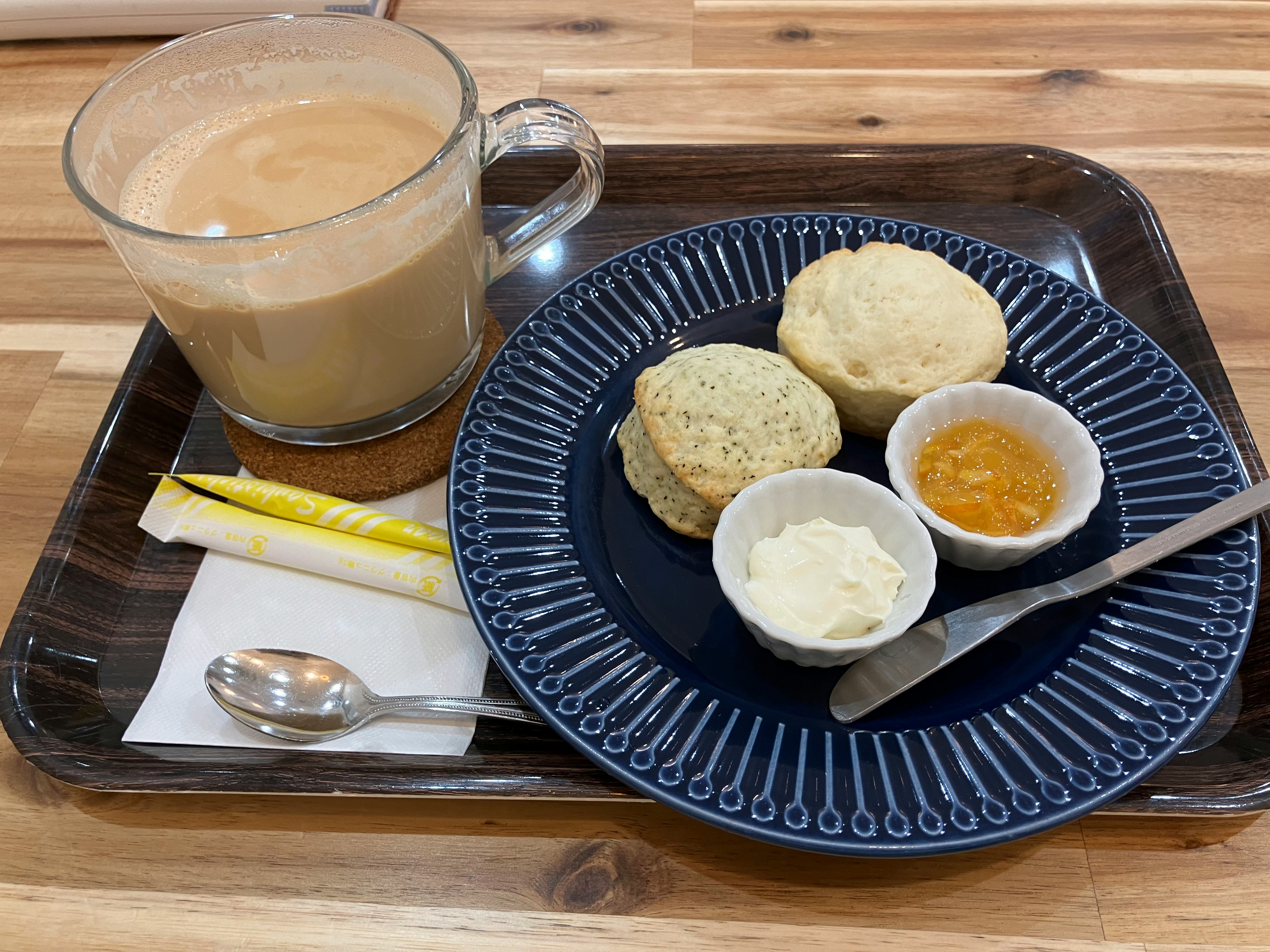 Una bandeja con café, scones, mantequilla y miel servidos en un plato azul