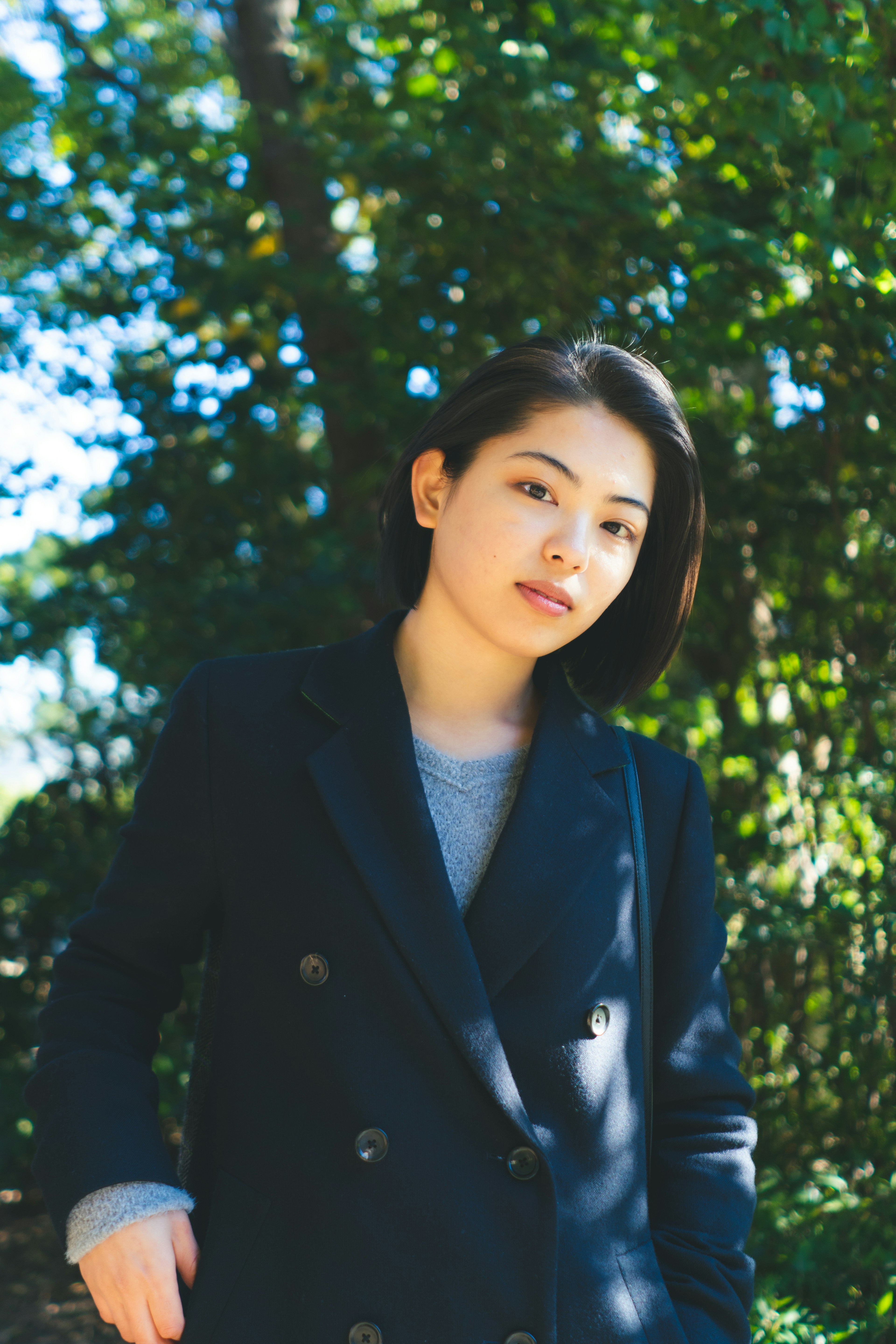 Portrait of a woman in a black coat against a green background