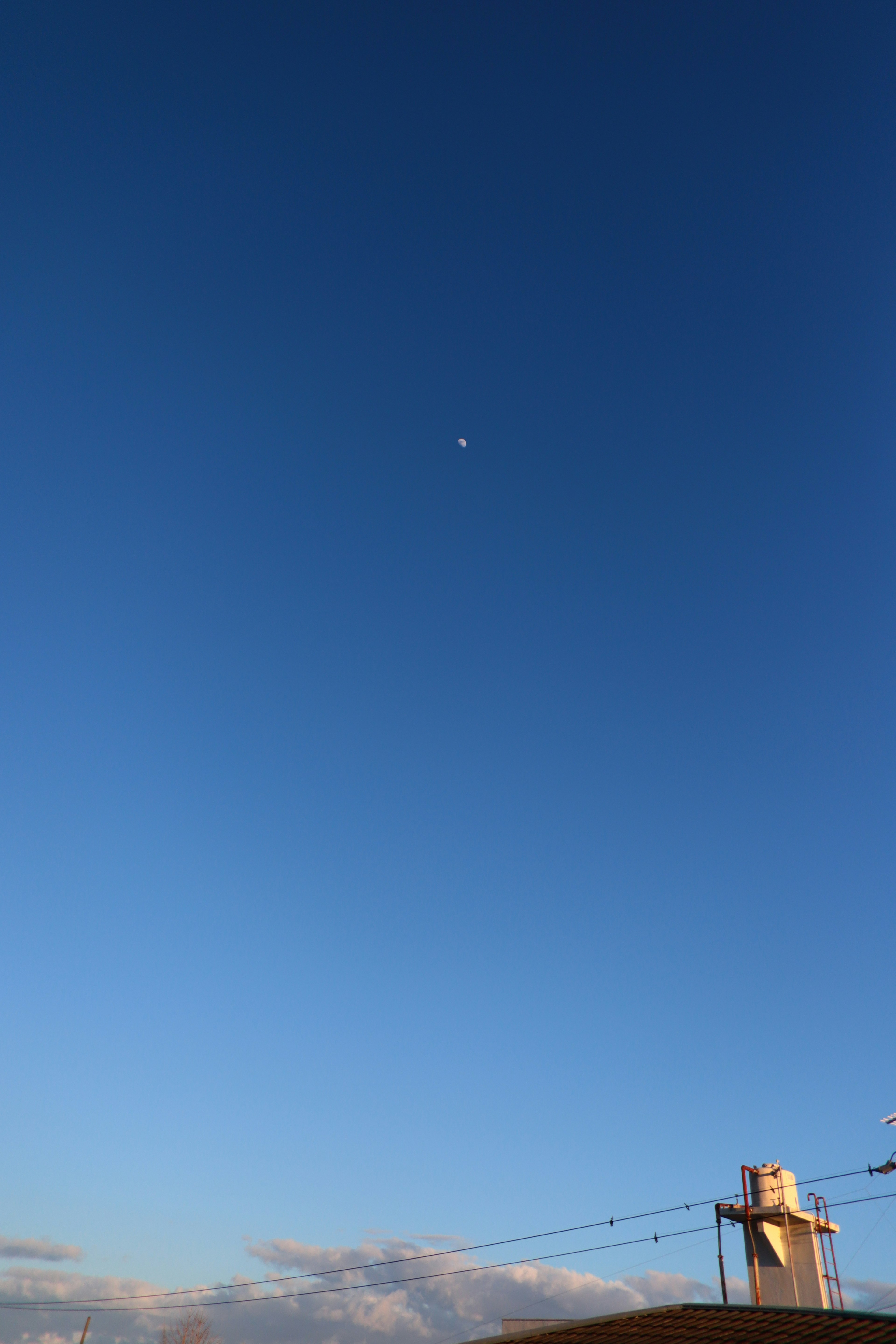 Langit biru cerah dengan titik putih kecil dan sebagian bangunan