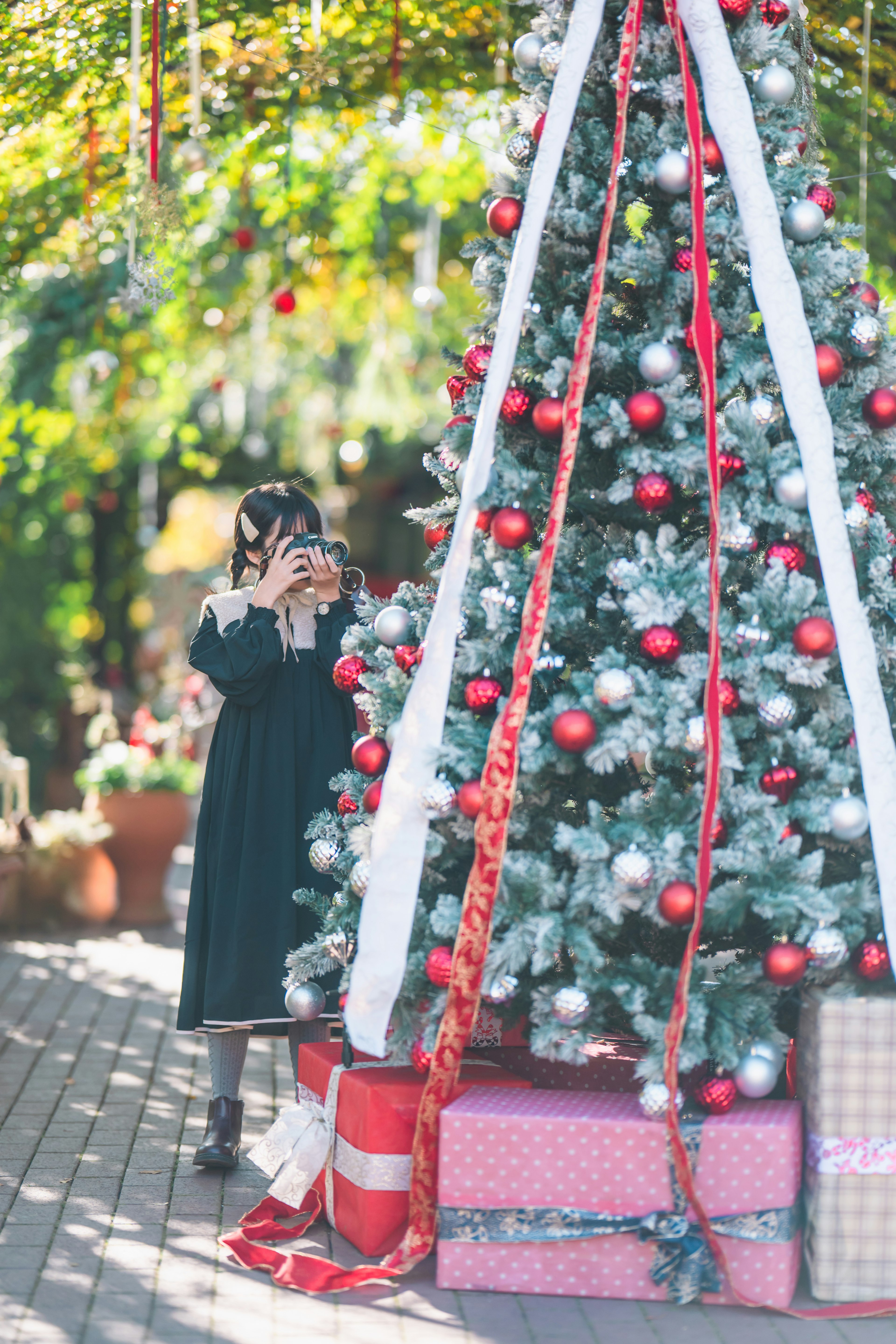 Un bambino con una macchina fotografica davanti a un albero di Natale