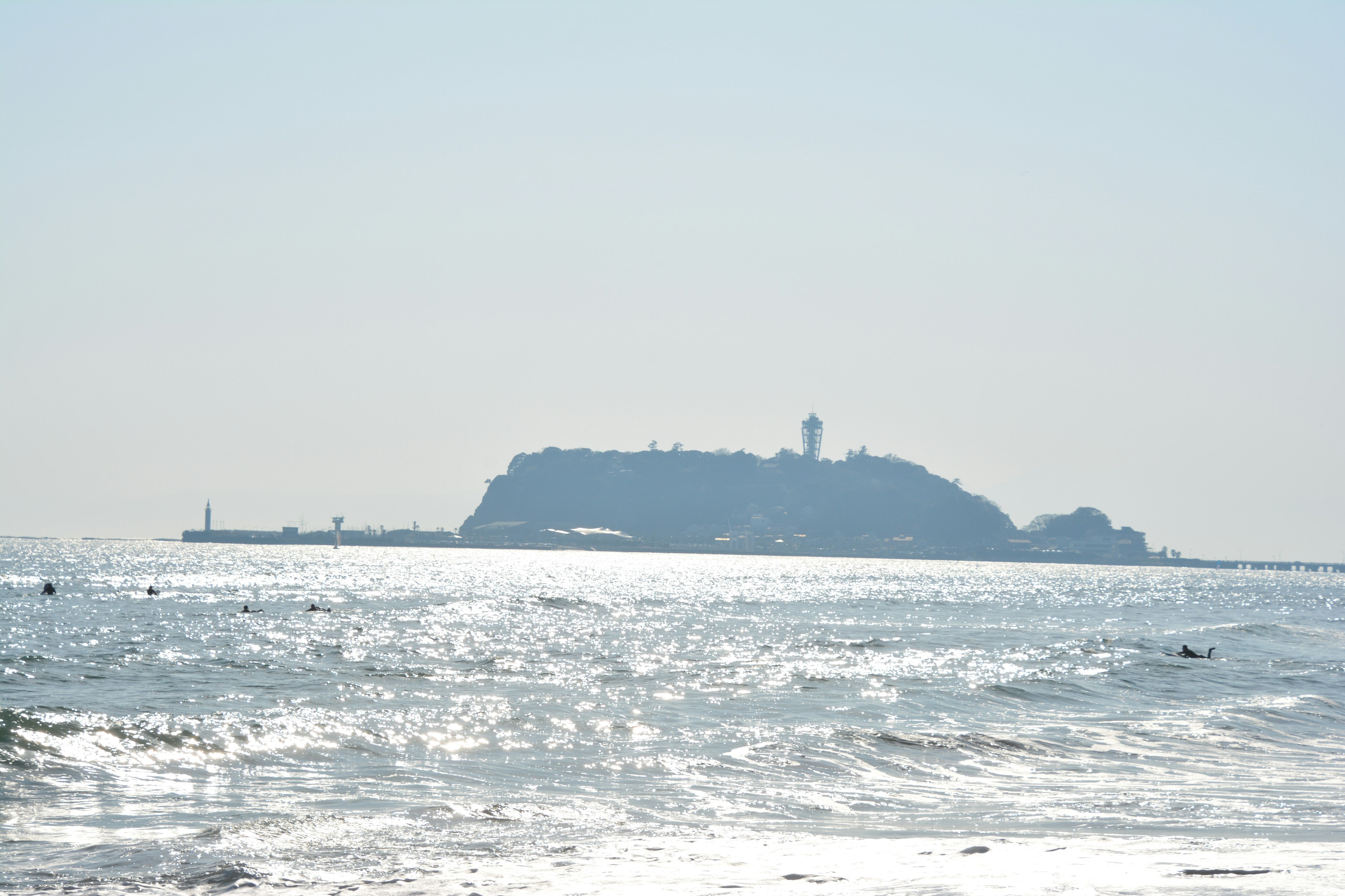 Scenic view of an island with a lighthouse in the ocean