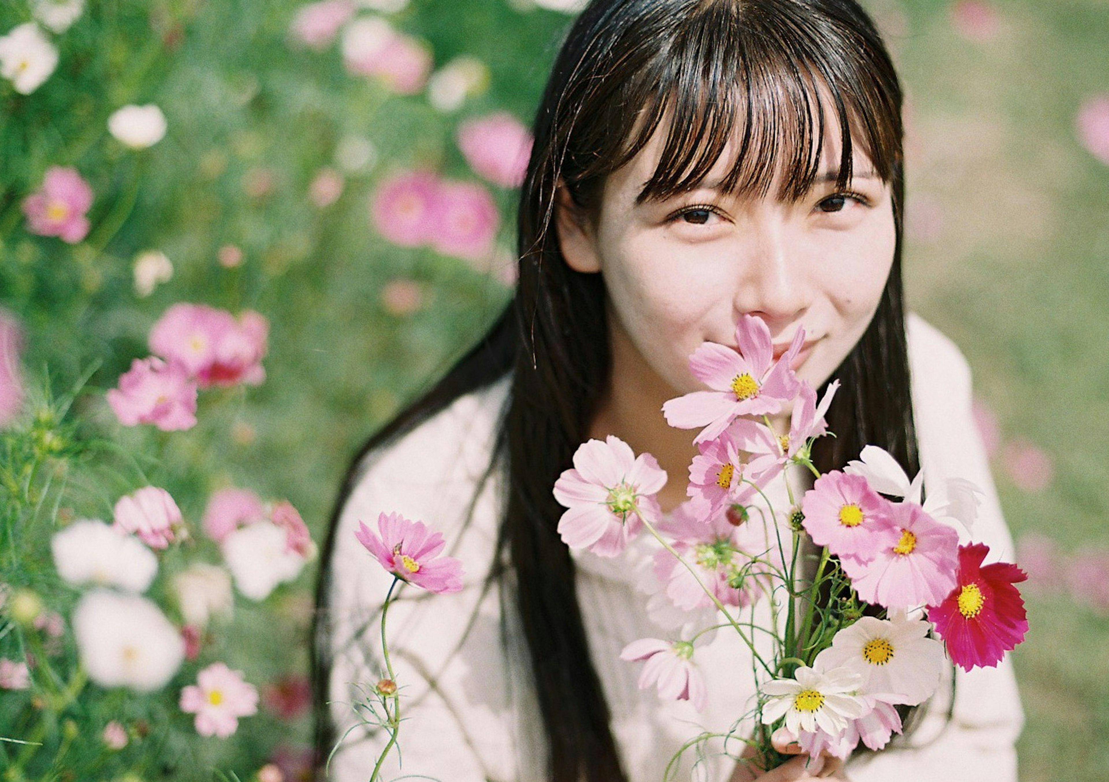 Une femme souriante tenant un bouquet de fleurs dans un paysage magnifique