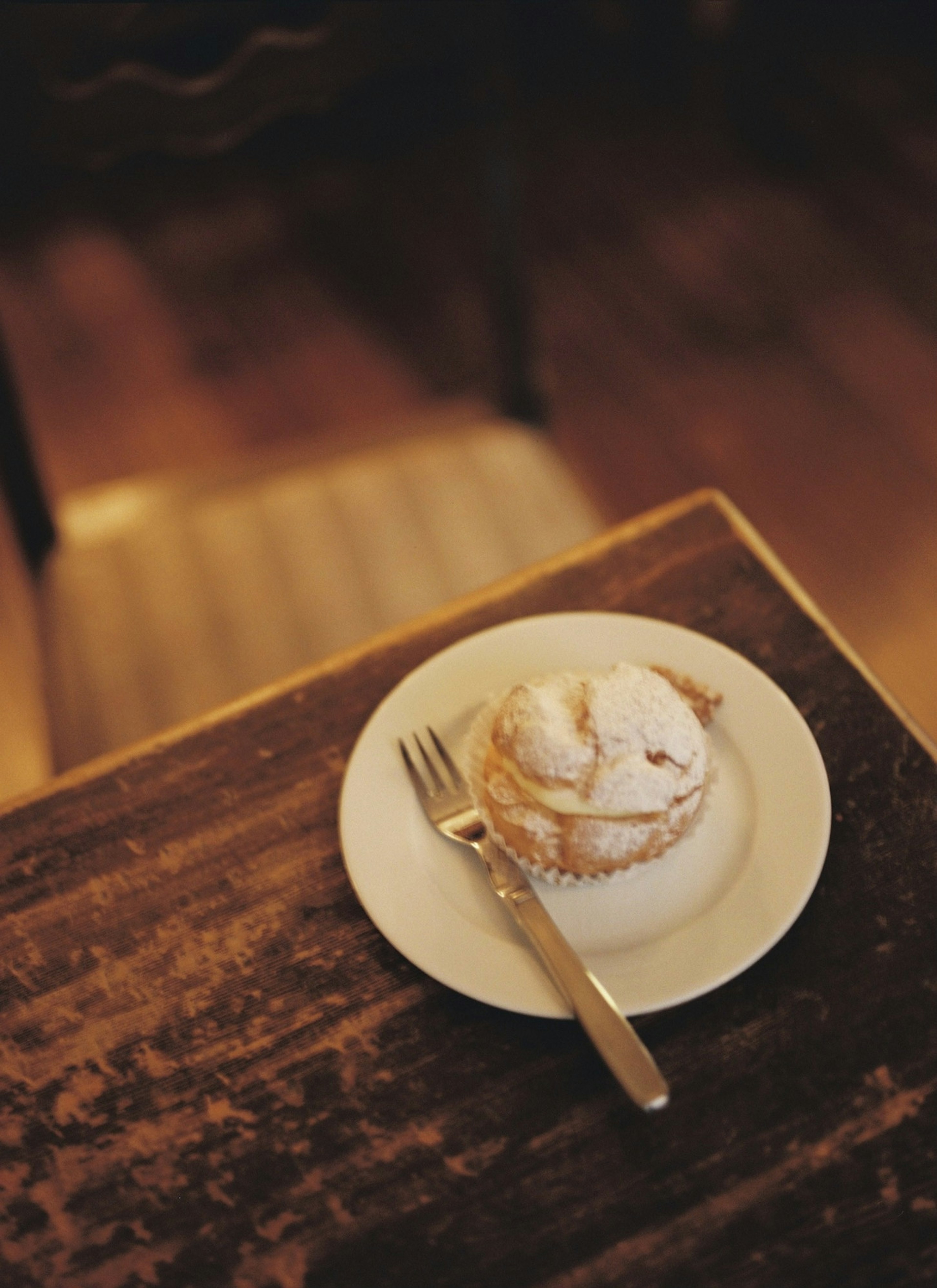 Dessert topped with cream on a plate placed on a wooden table