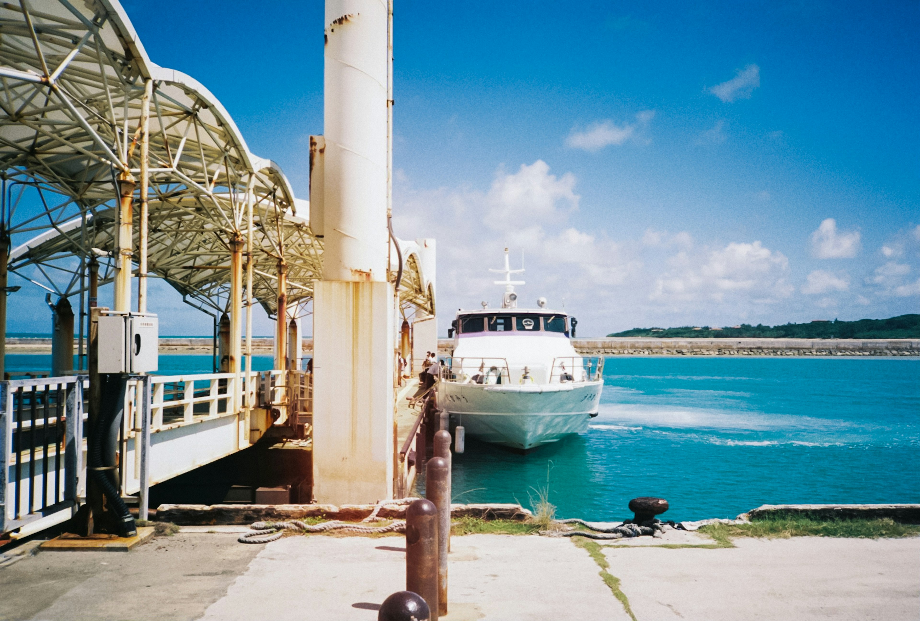 Ein weißes Boot, das einem Pier auf einem blauen Meer näher kommt