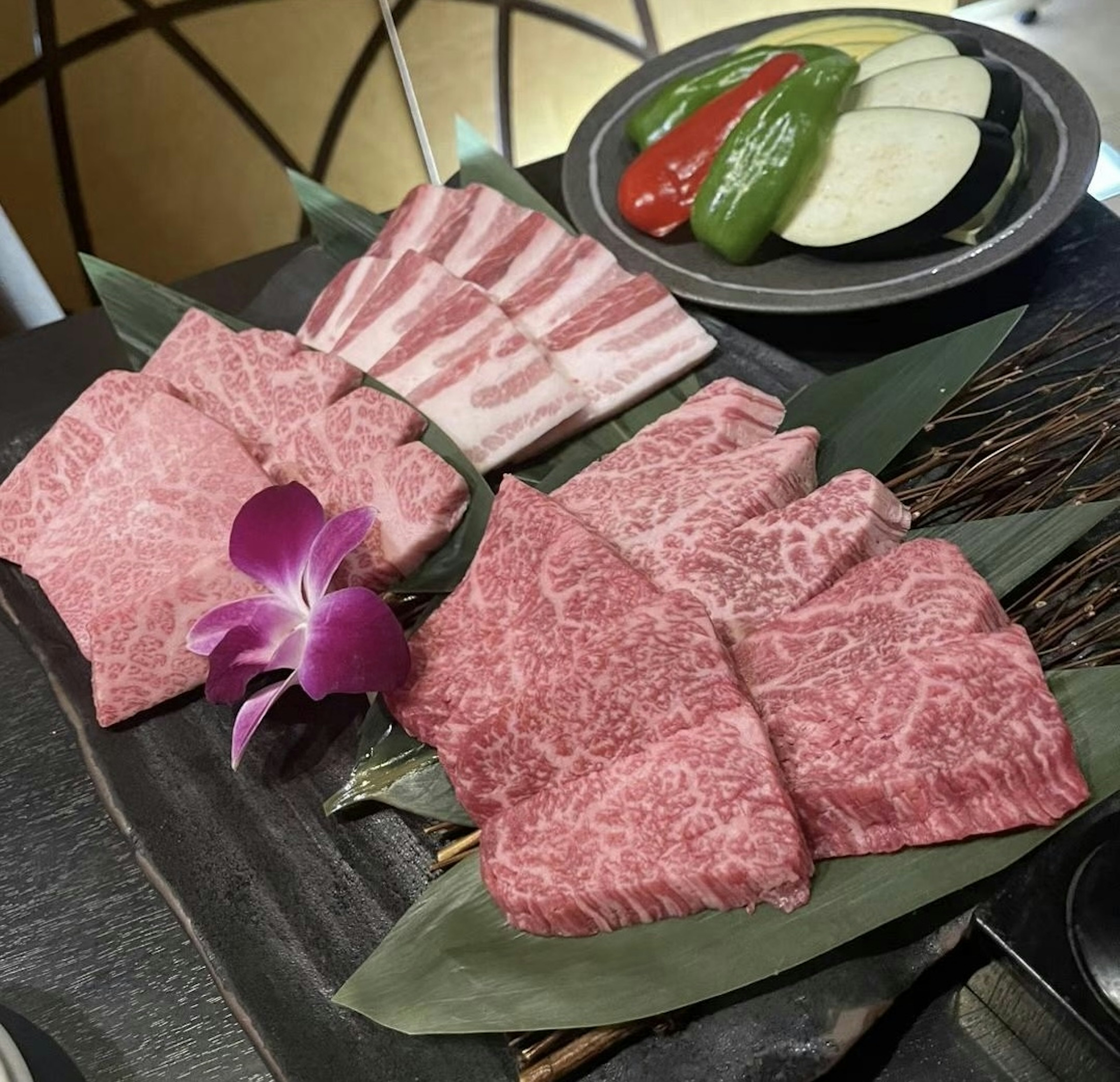 Hermosa bandeja de carne Wagyu con flor morada y verduras