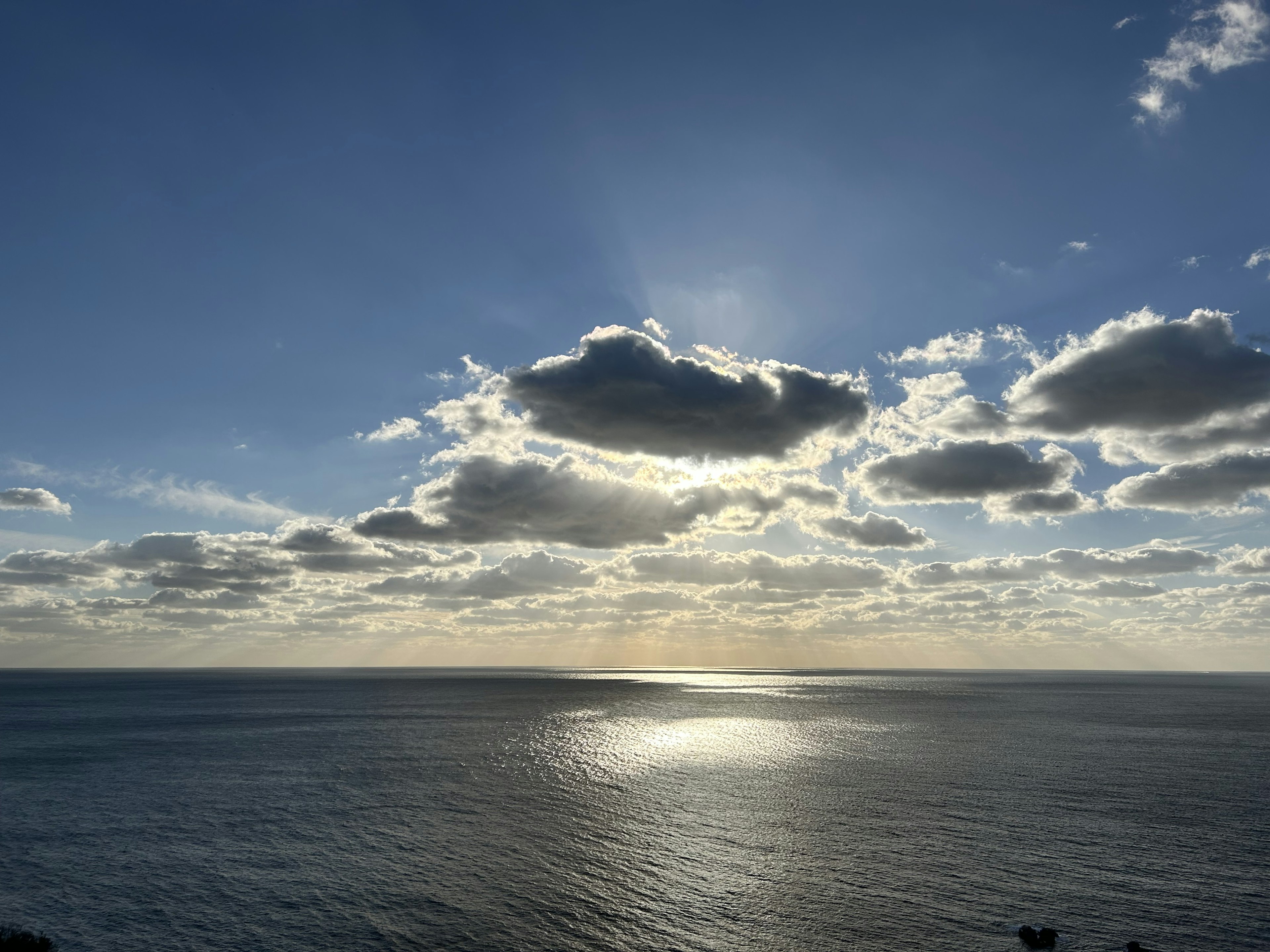 Malersiche Aussicht auf den Ozean unter einem blauen Himmel mit Wolken Sonnenlicht spiegelt sich im Wasser