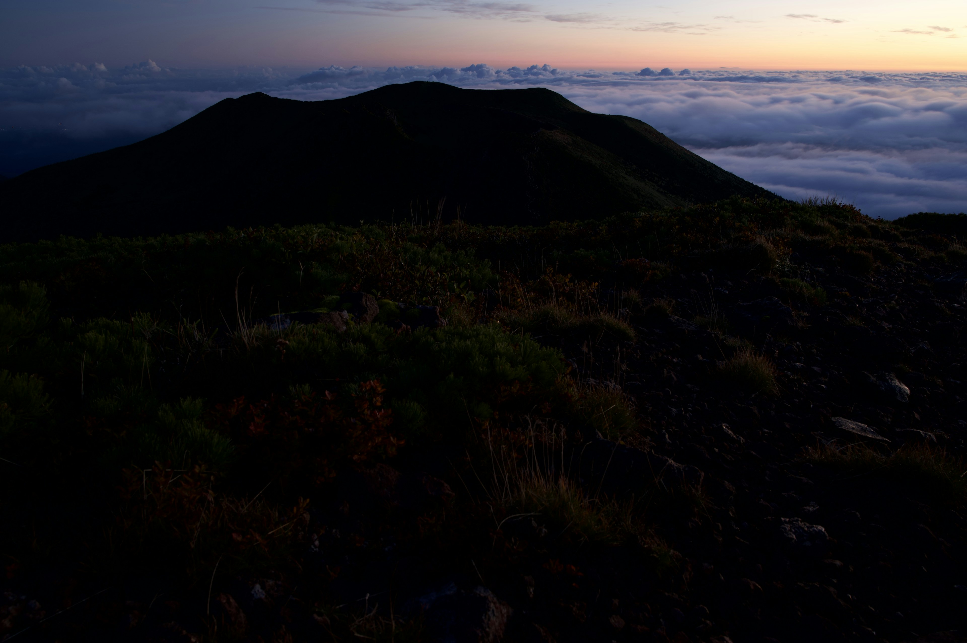 Silhouette of a mountain shrouded in mist with a twilight sky