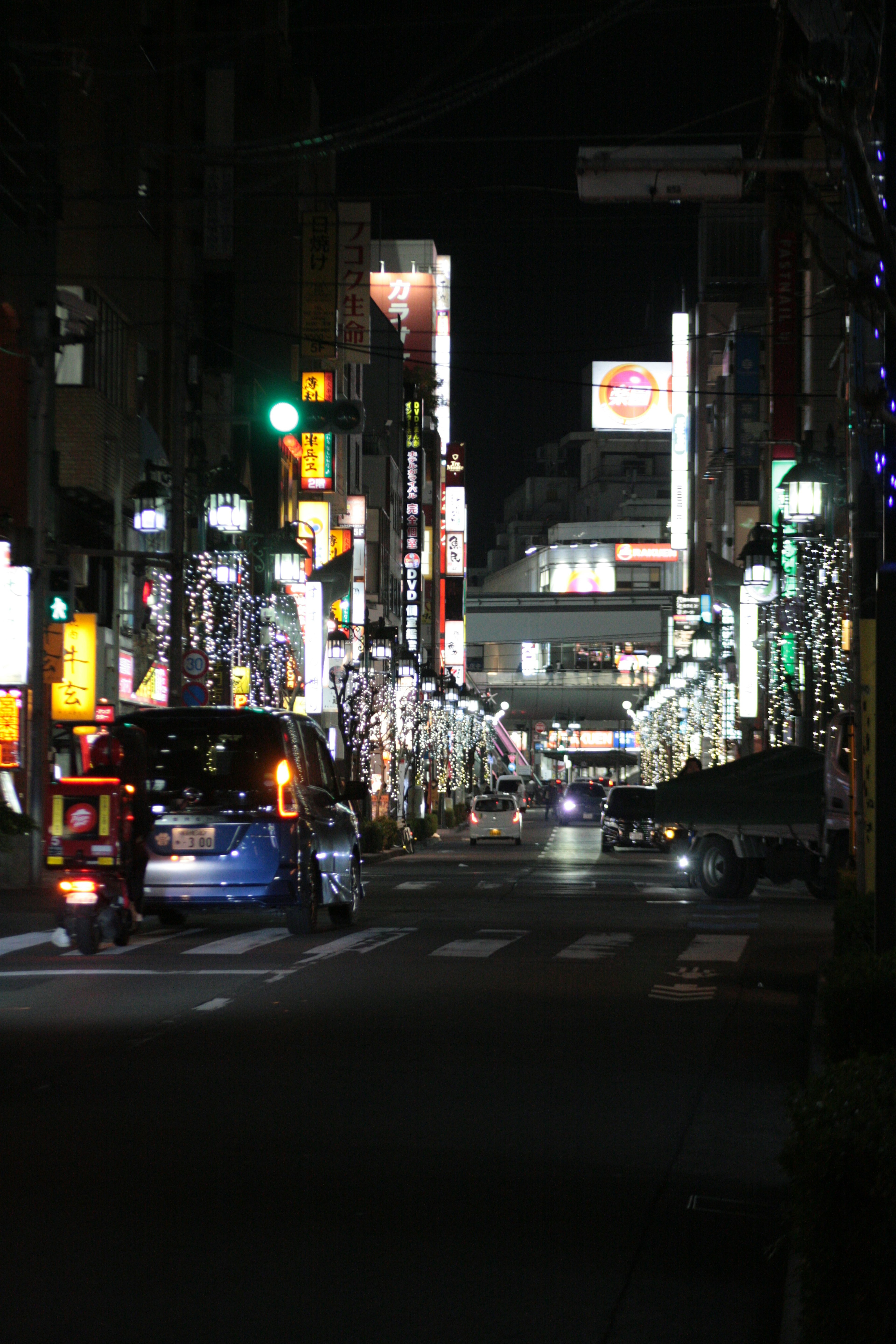 Una calle iluminada por la noche con un vehículo pasando