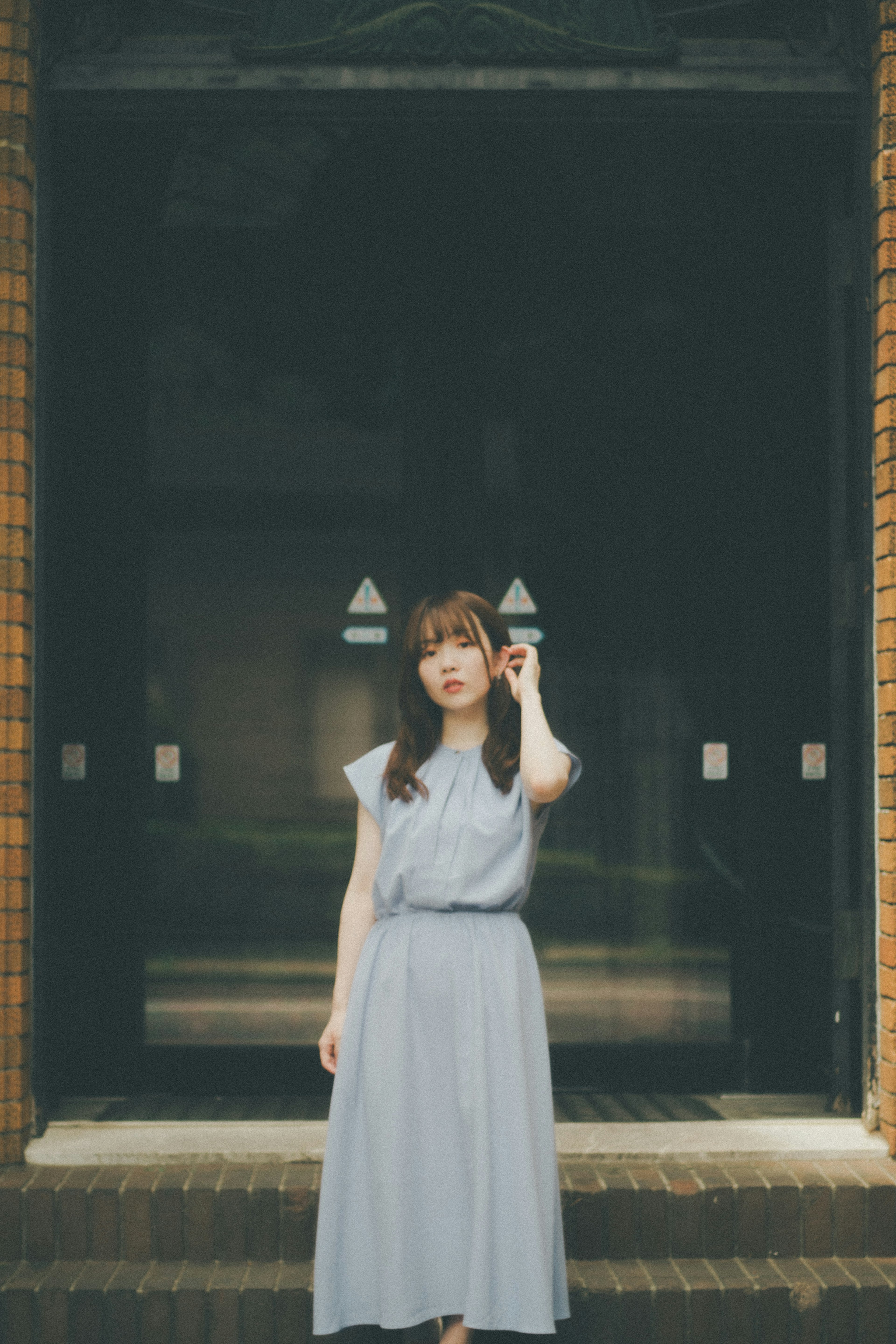 Woman in a blue dress standing in front of a black building