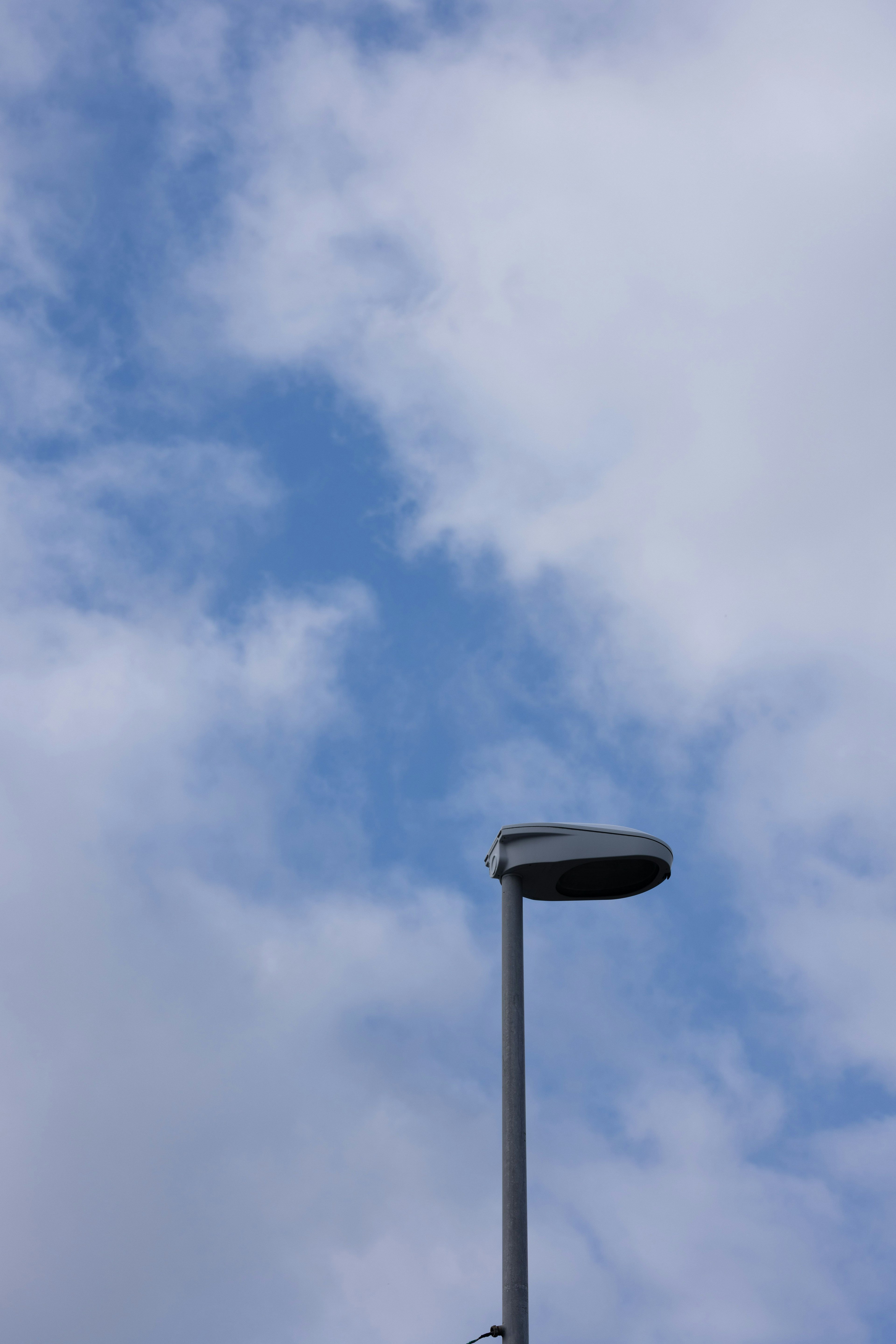 Farola contra un fondo de cielo azul y nubes blancas