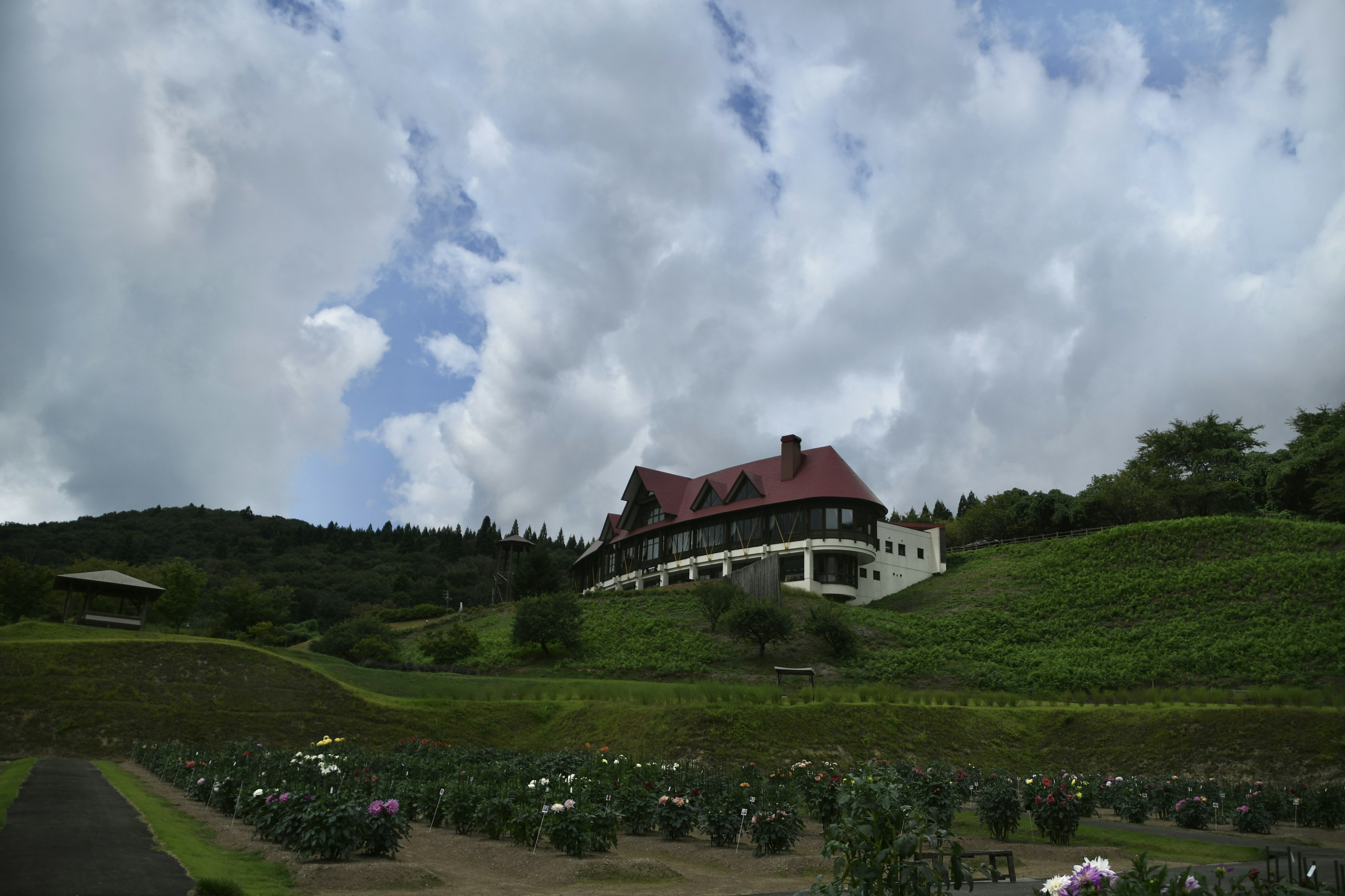 European-style building with a red roof on a green hill under a blue sky