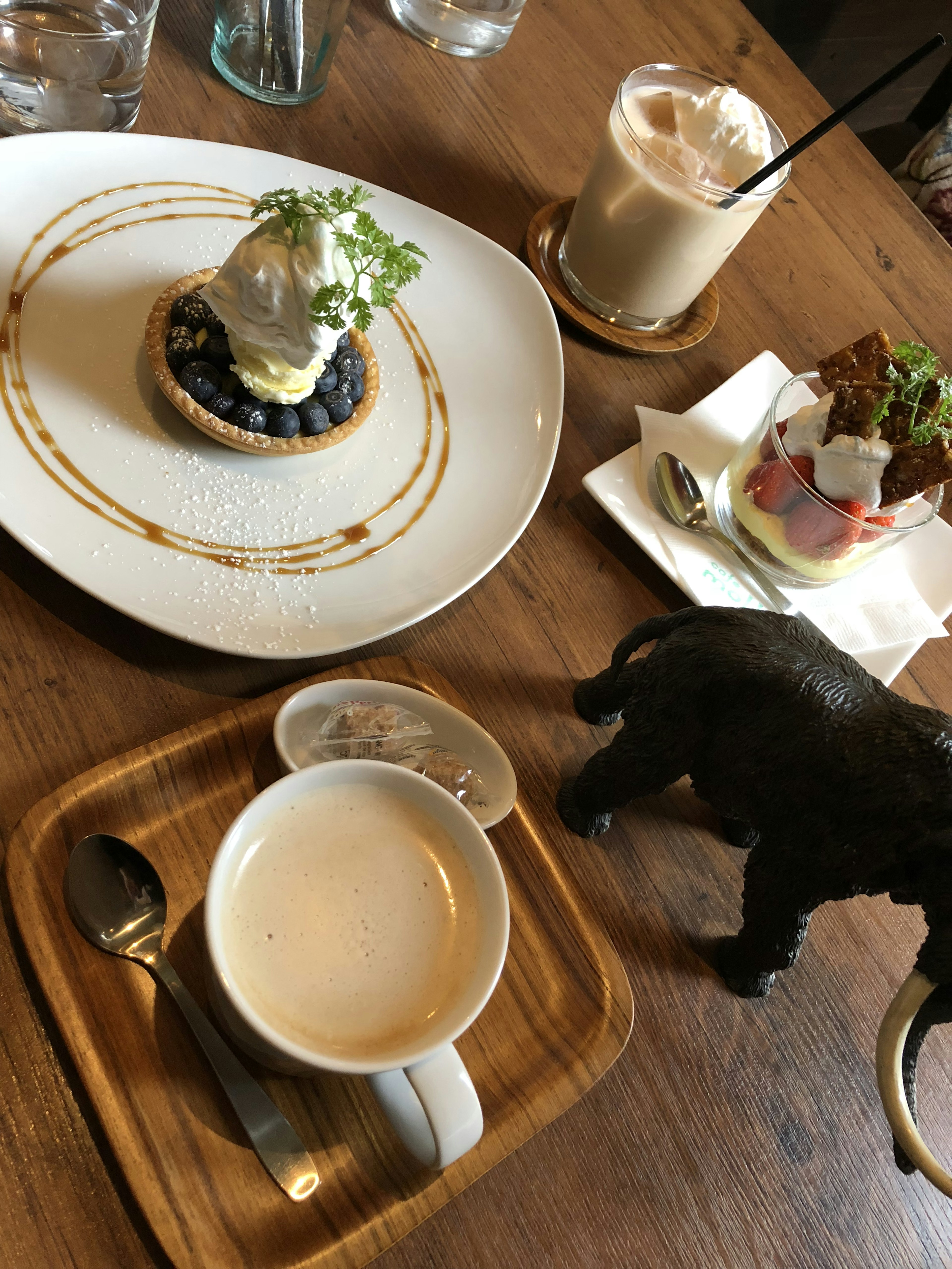 Ein schön angerichteter Dessertteller mit einer Heidelbeertorte und Eis sowie einer Tasse Kaffee auf einem Holztisch