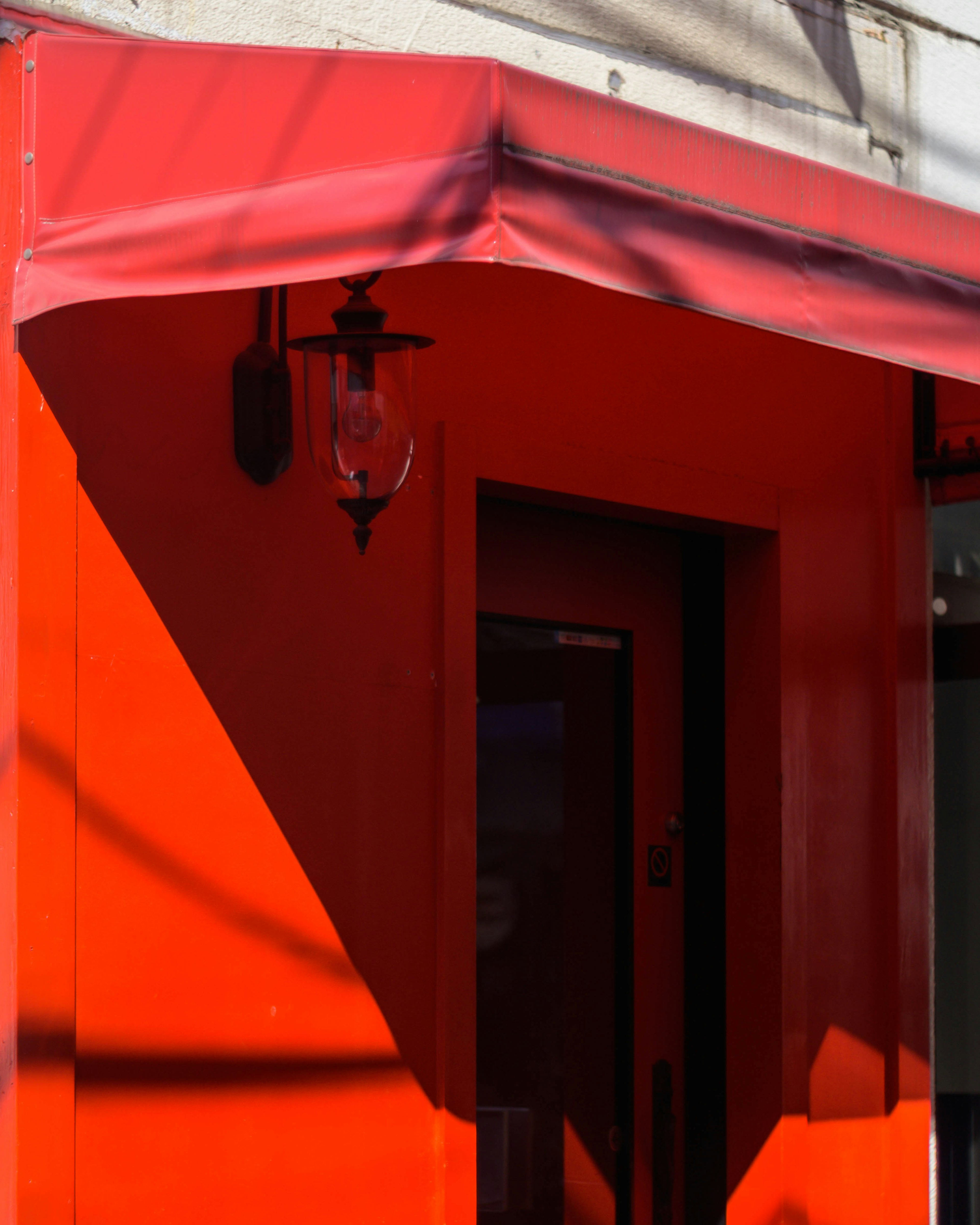 Angolo di un edificio con parete rossa vivace e awning con porta